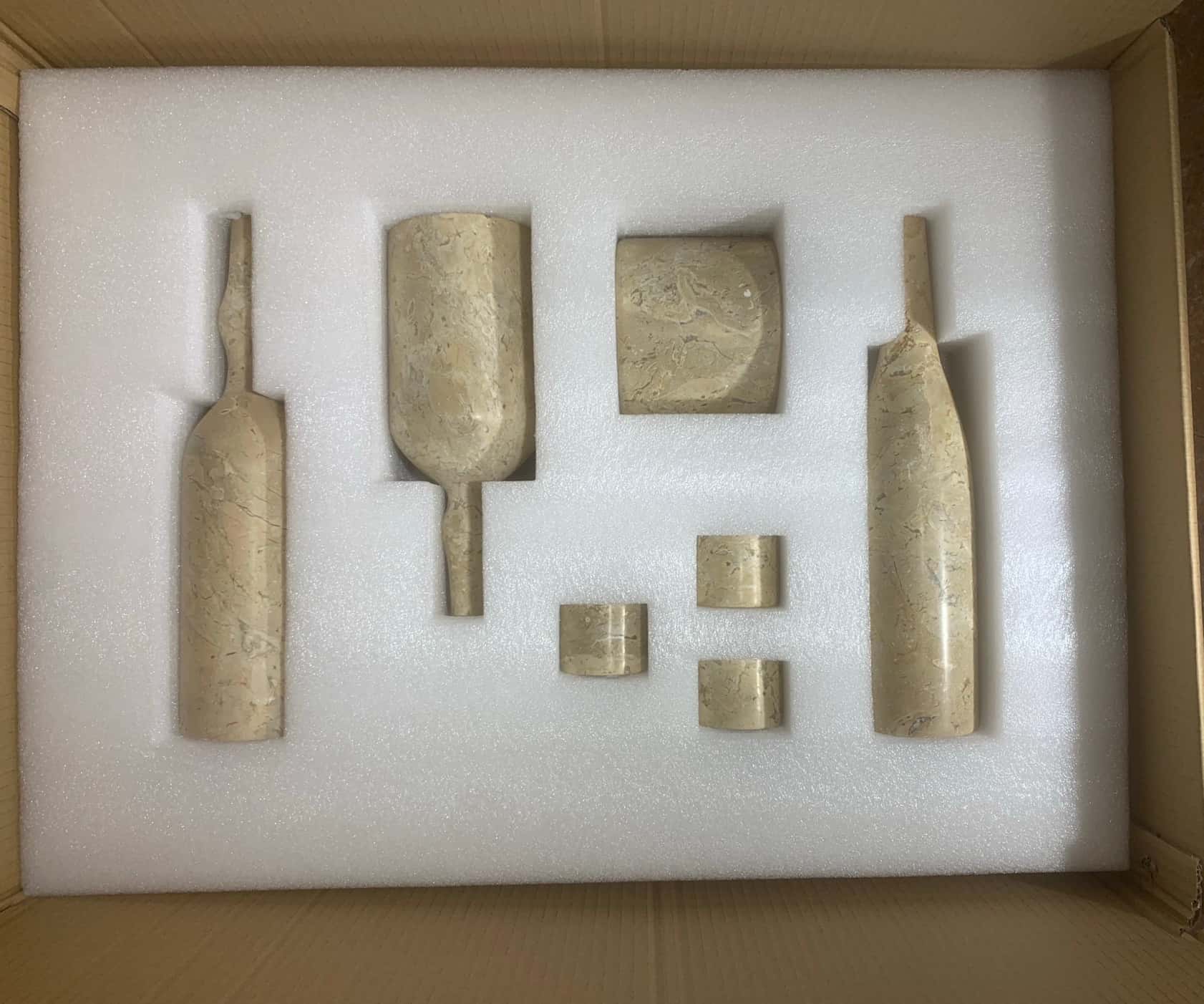 Custom molded protective foam packaging securely holding all seven Amber Gold natural marble decor pieces in shipping box.