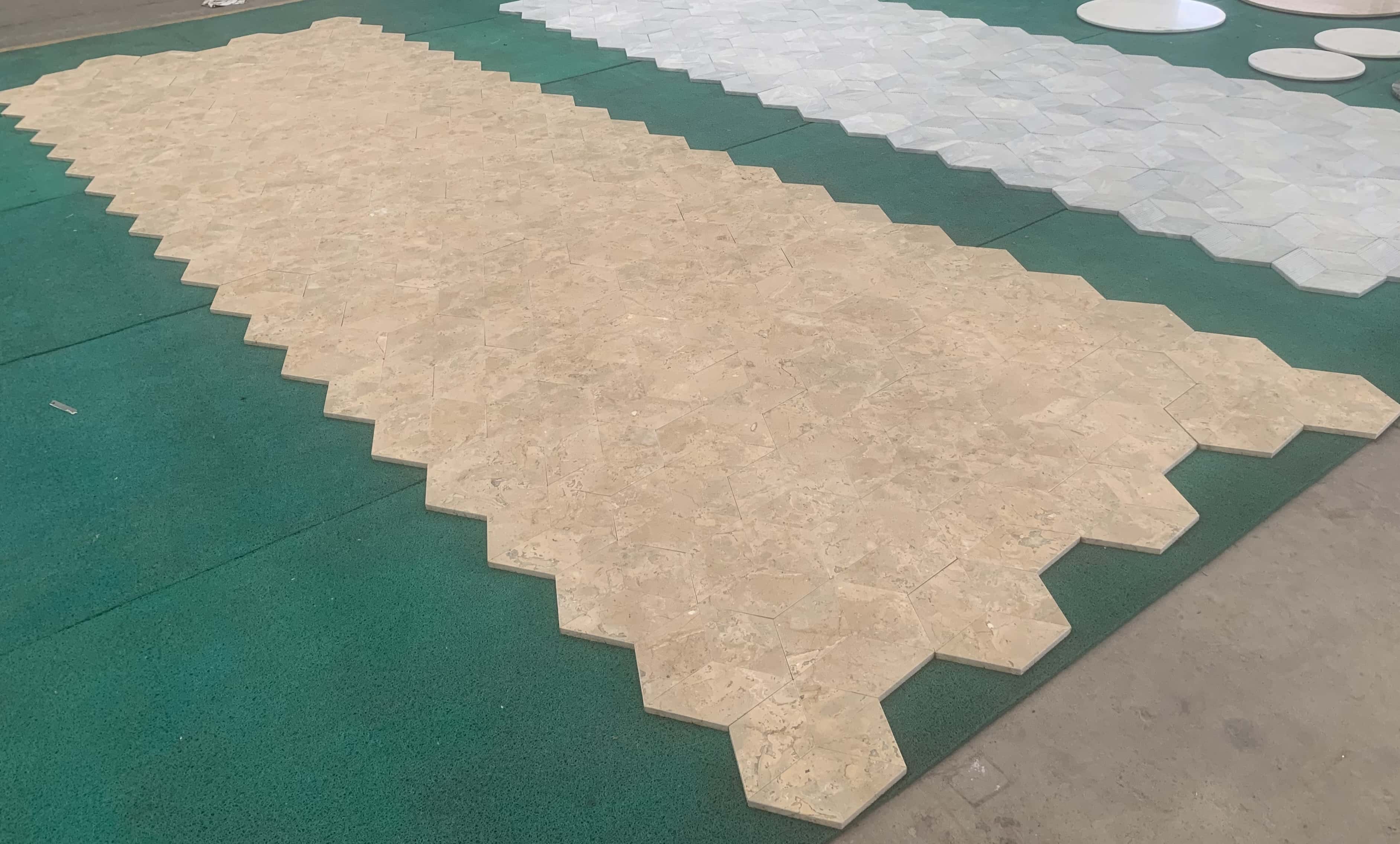 Wide angle factory dry-lay view of premium Honed Amber Gold natural marble hexagon tiles laid in a clean row.