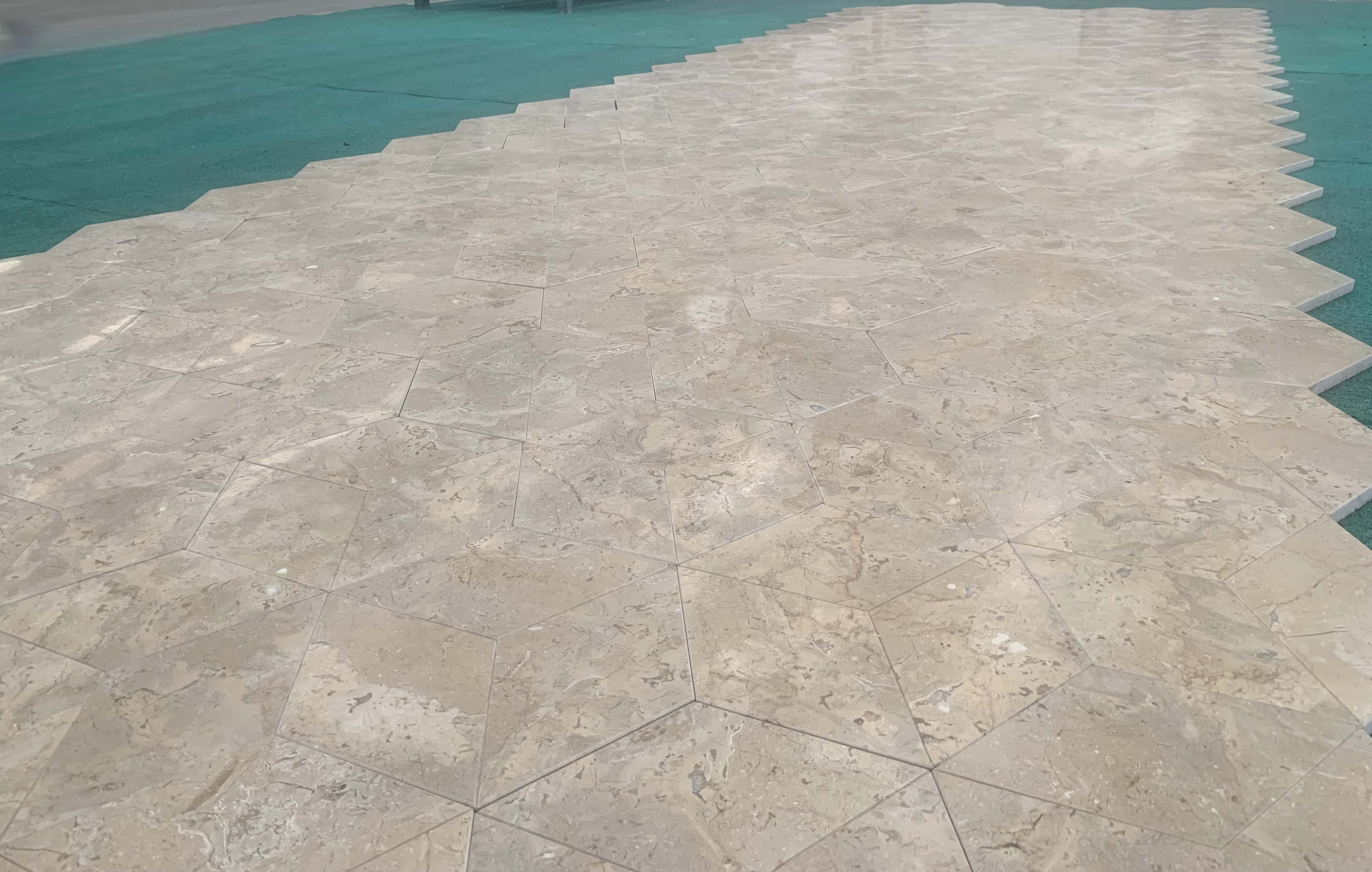 Detailed close-up of factory dry-lay Honed Amber Gold marble hexagon tiles showing natural veining and finish.