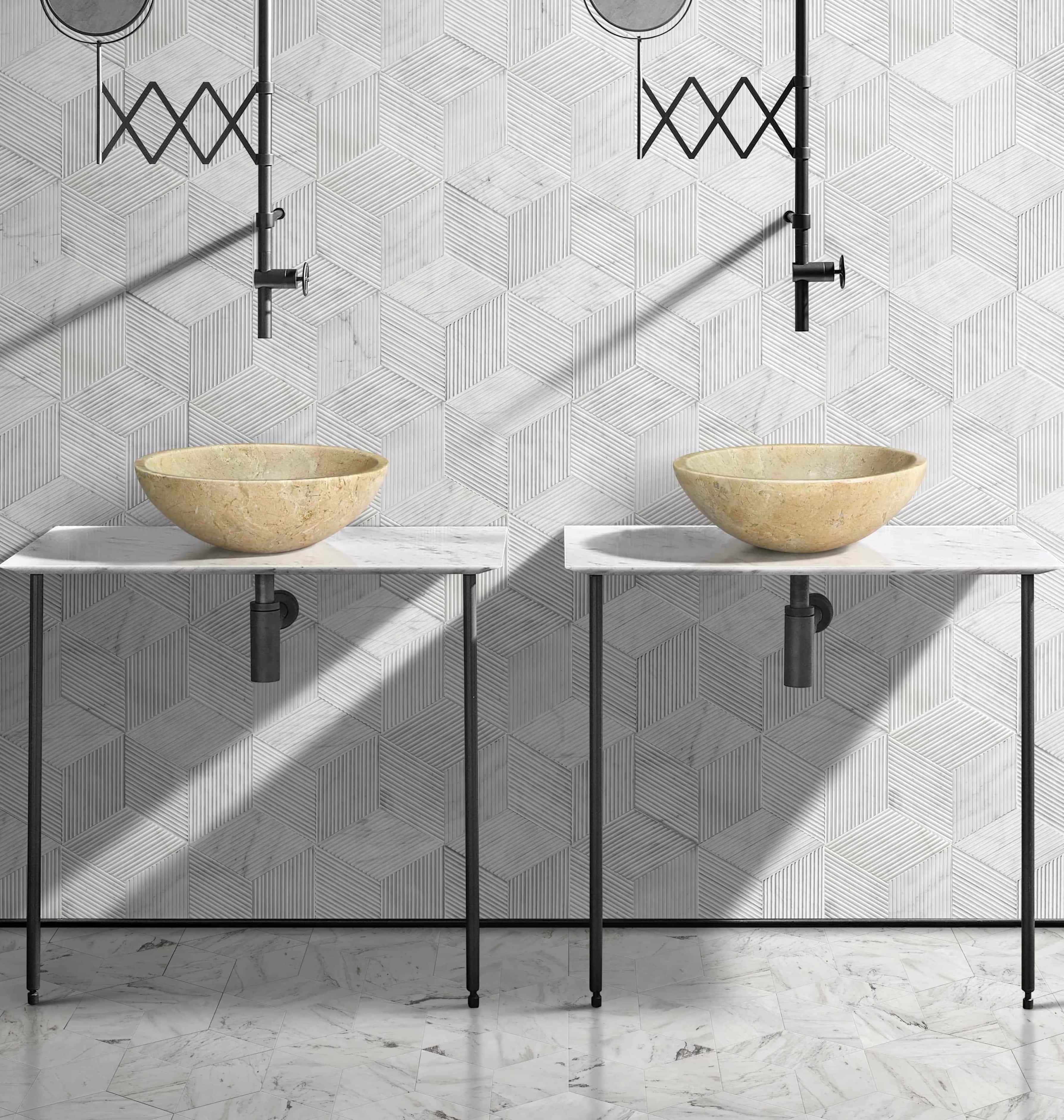 Two Amber Gold marble vessel sinks on white consoles with hexagon textured tile wall and polished floor, industrial bathroom.