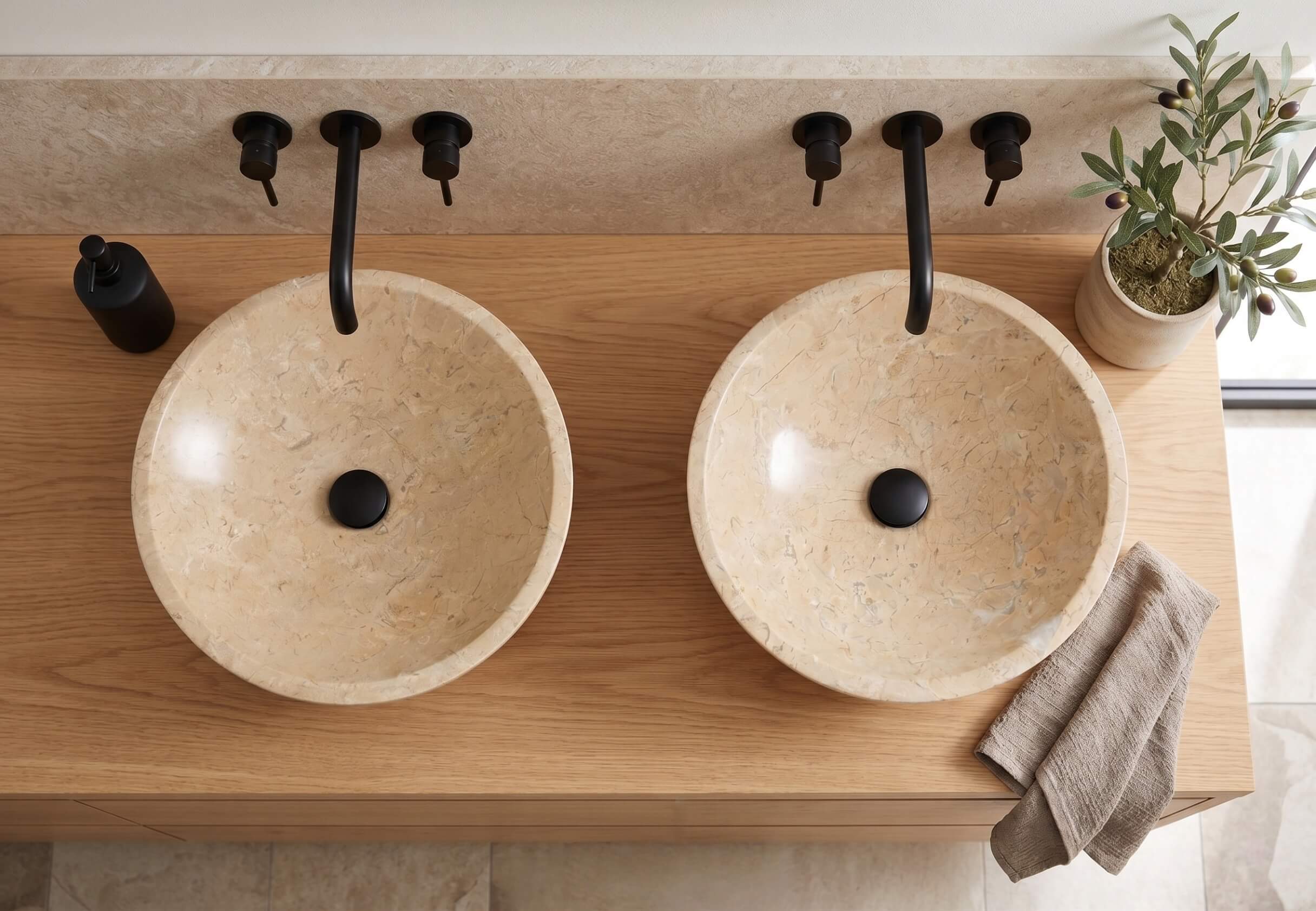 Top-down view of two Amber Gold marble vessel sinks on light oak vanity with black wall faucets in wabi-sabi Mediterranean bathroom.