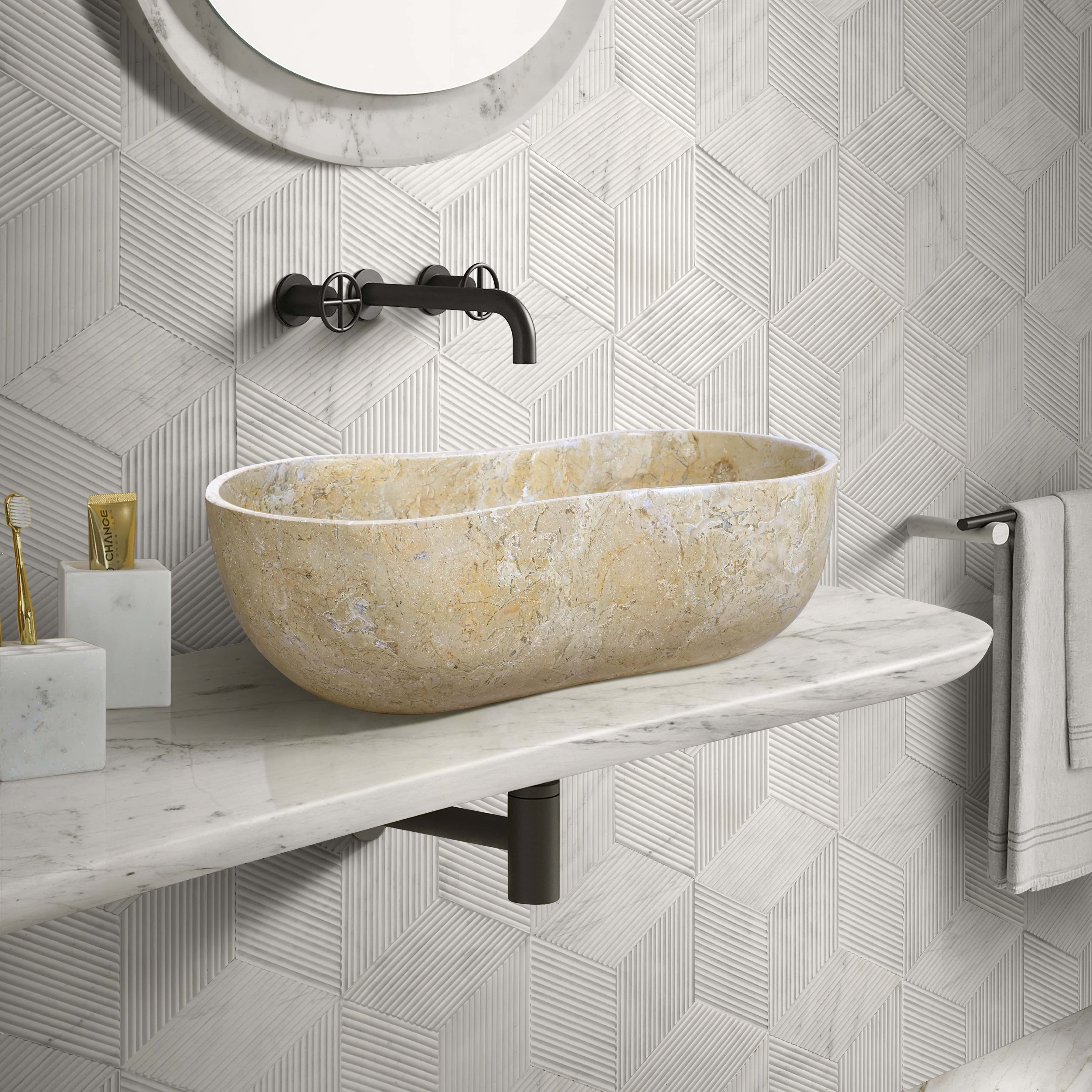 An Amber Gold marble Wave vessel sink on white marble against Snow Mountain White textured hexagon wall tile.