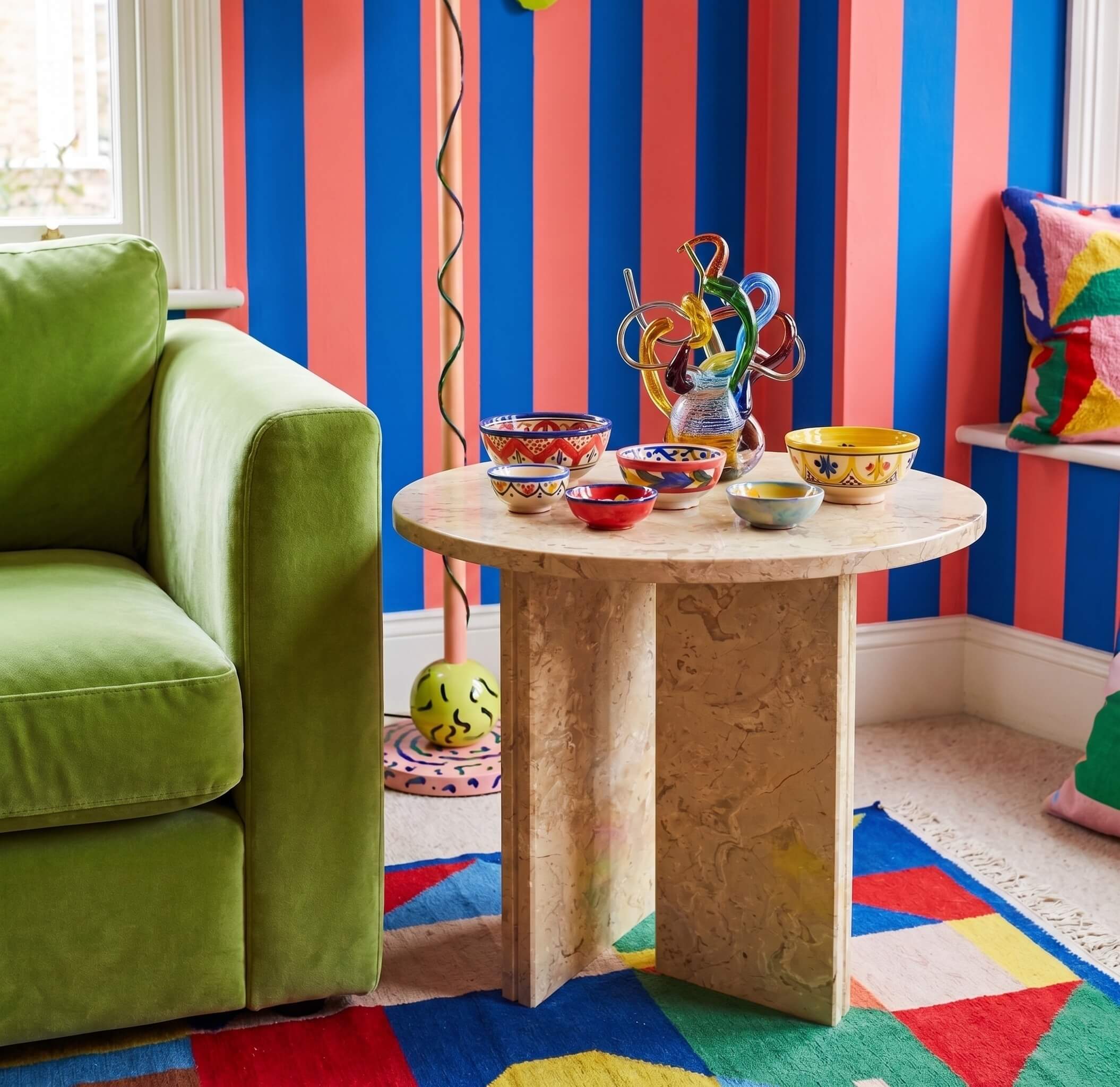 Round 45cm Amber Gold marble end table styled with colorful ceramic bowls in a vibrant eclectic living room.