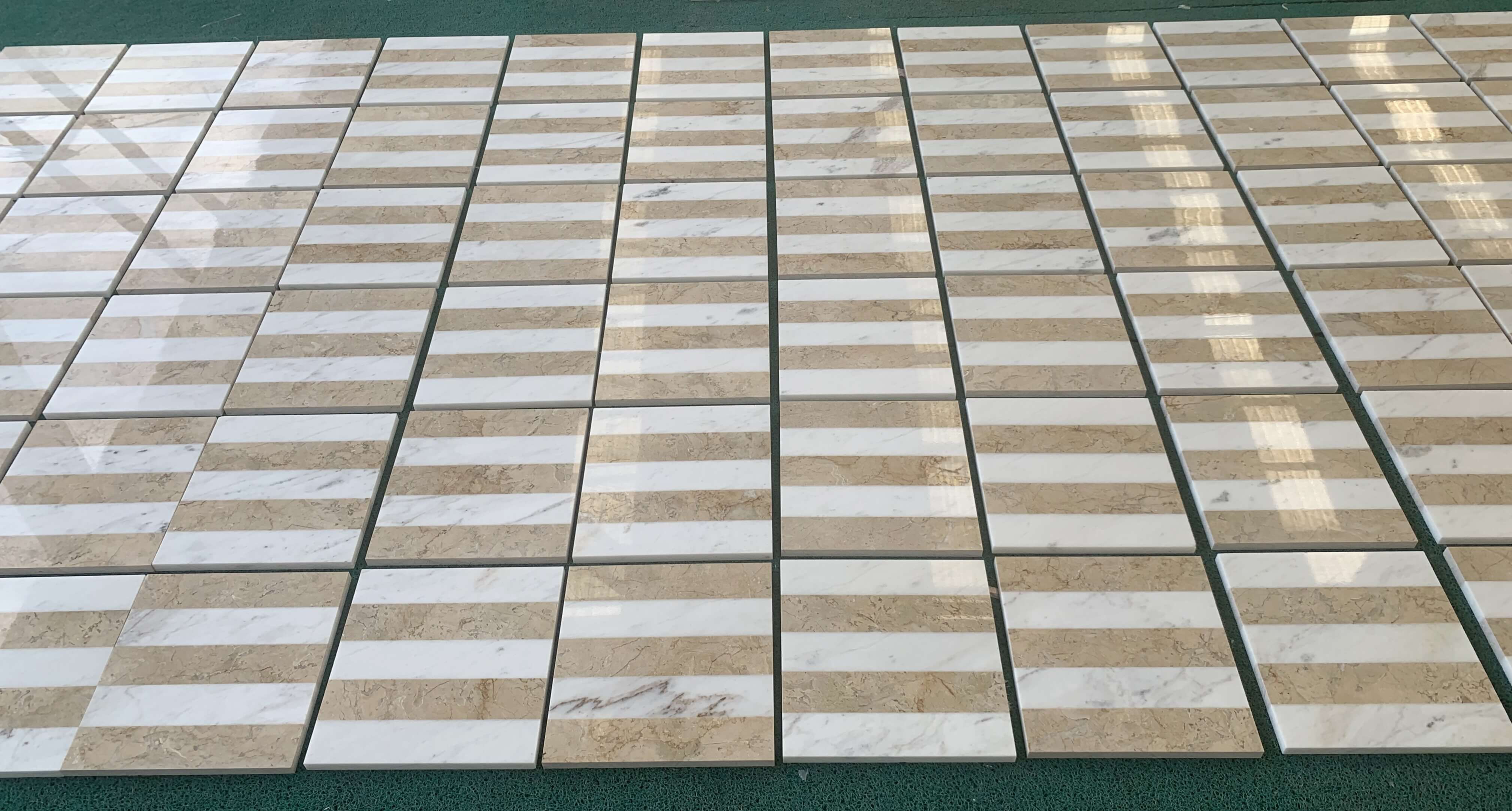 Factory dry-lay quality check of White and Gold polished waterjet marble tiles arranged in a horizontal stripe layout.
