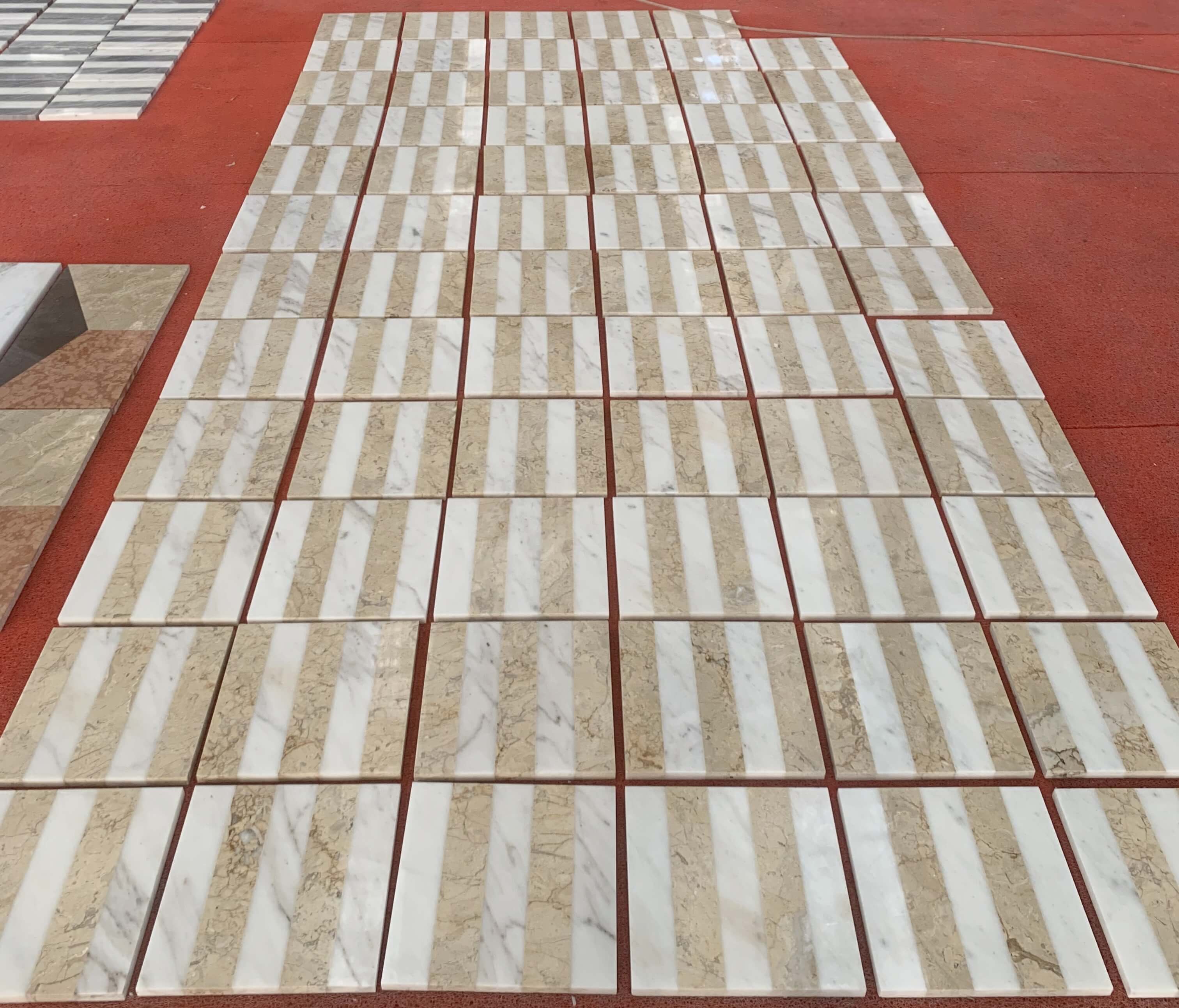 Natural stone variation inspection of White and Gold waterjet marble tiles aligned in vertical stripe orientation.