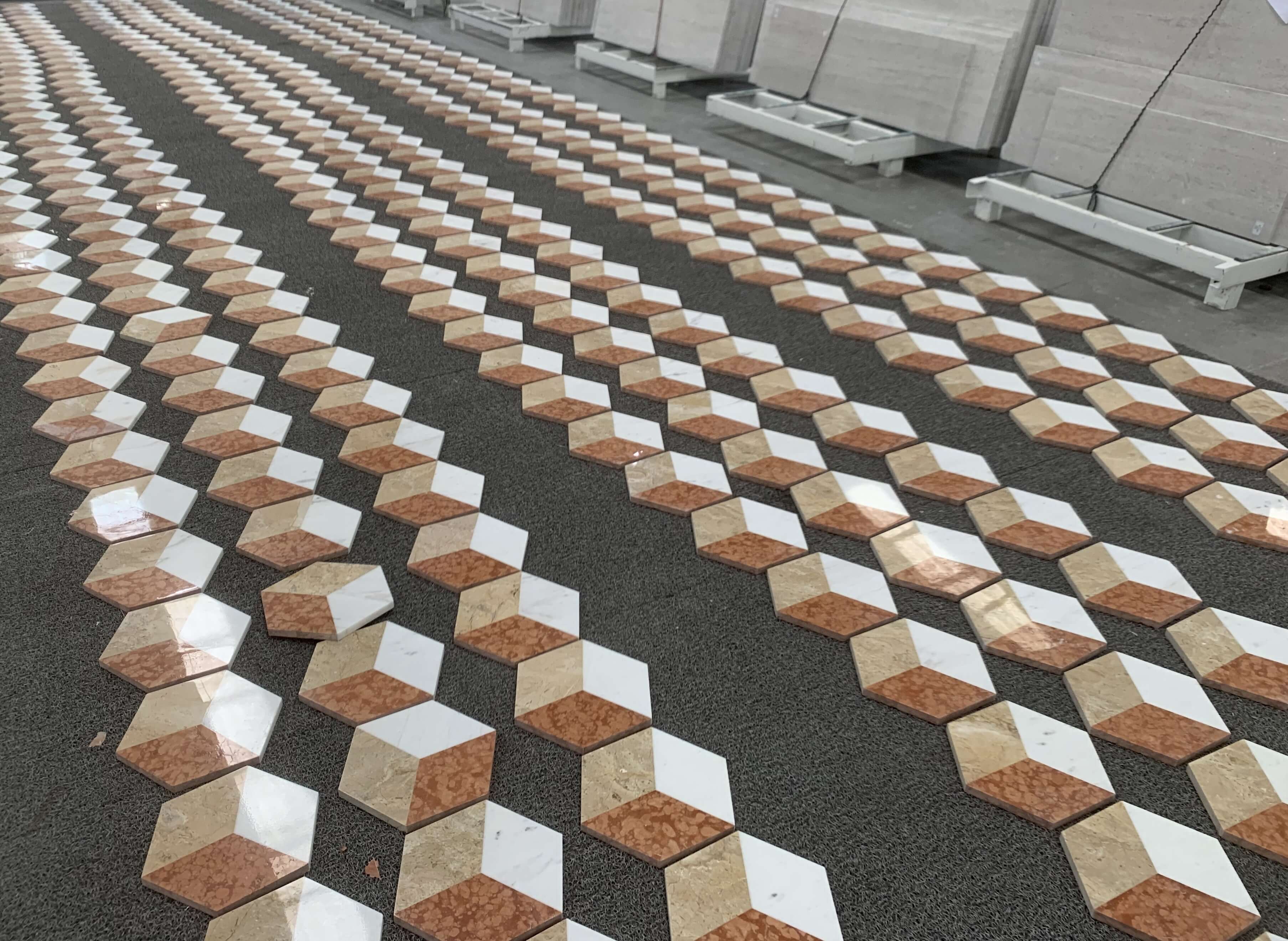 Perspective dry-lay inspection of white, gold, and red marble hexagon floor tiles checking pattern seamless alignment.