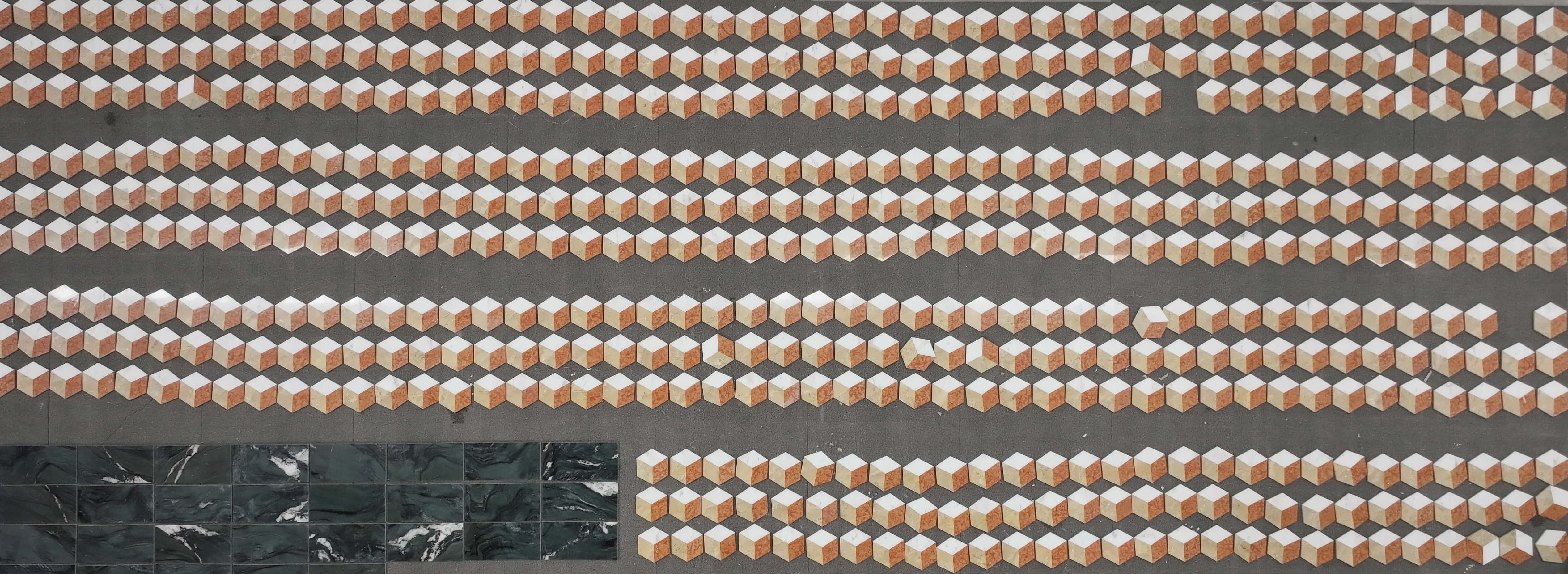 Overhead view of bulk 3D cube hexagon waterjet marble tiles arranged in rows on factory floor for quality inspection.