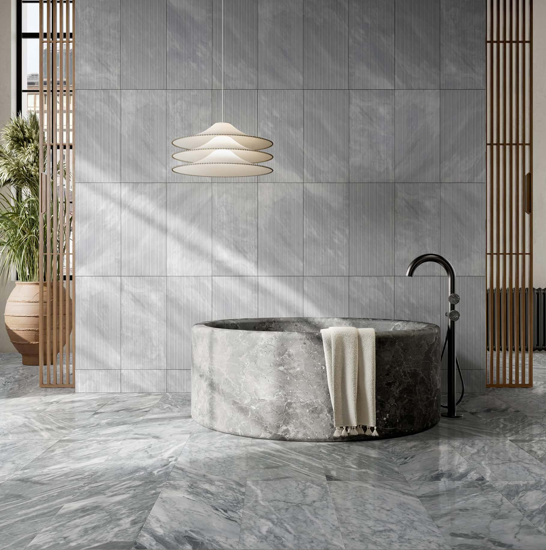 Minimalist bathroom with round stone tub, 12x24 Carrara Gray polished floor tiles, and matching textured wall tiles.