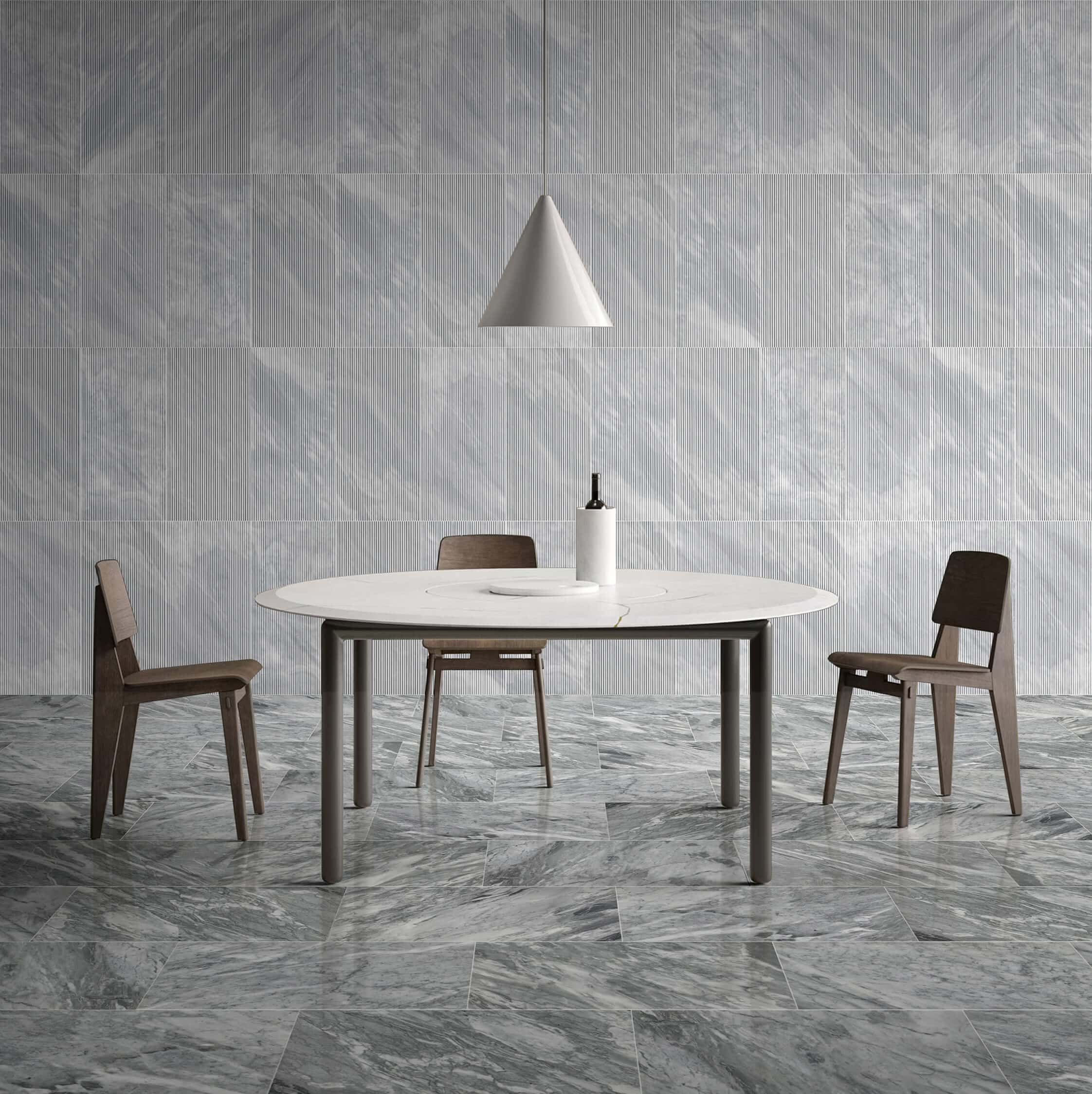 Modern dining room featuring round table with 12x24 Carrara Gray polished floor tiles and fluted textured wall tiles.
