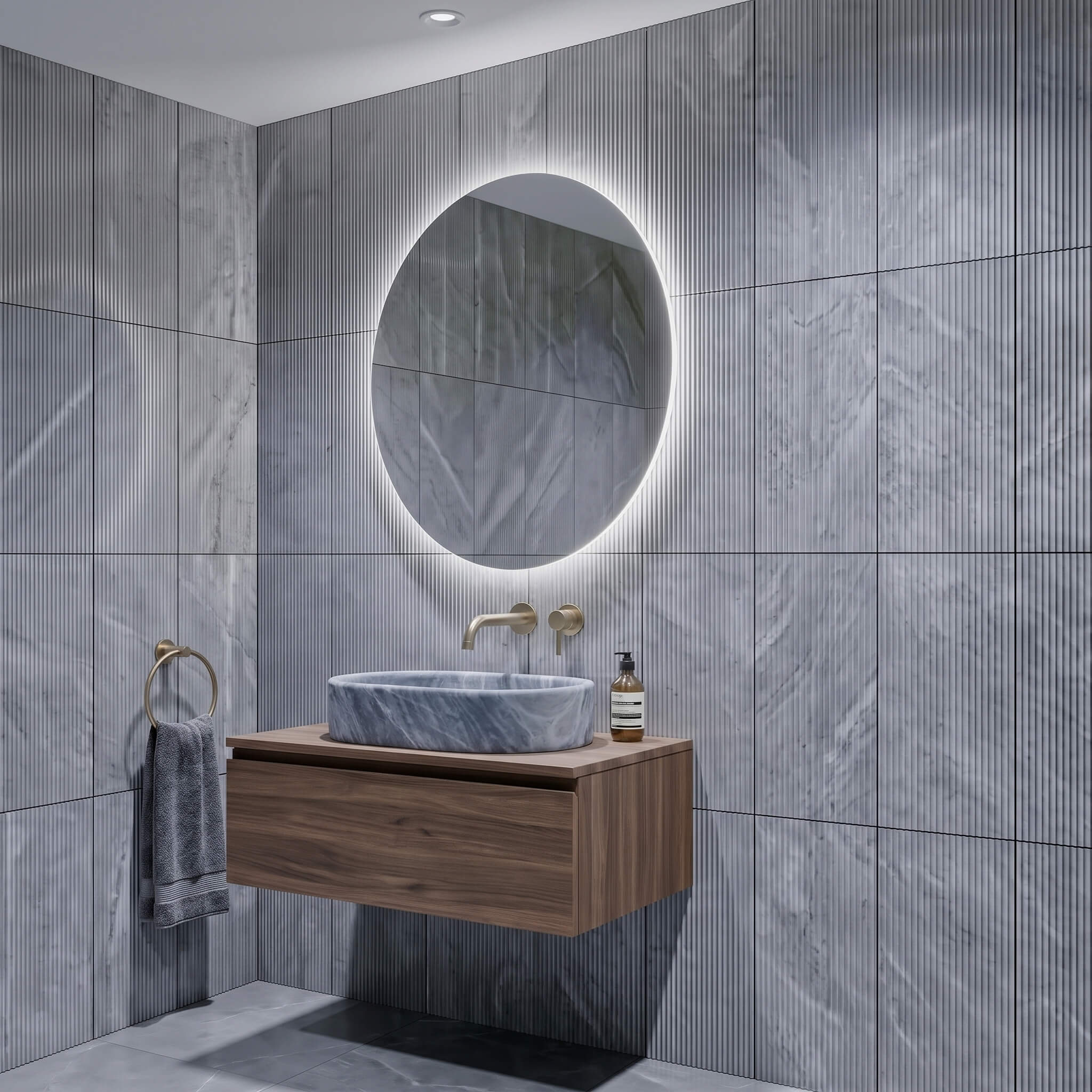 Angle view of a bathroom vanity and honed oval marble vessel sink against 12x24 Carrara gray fluted wall tiles.