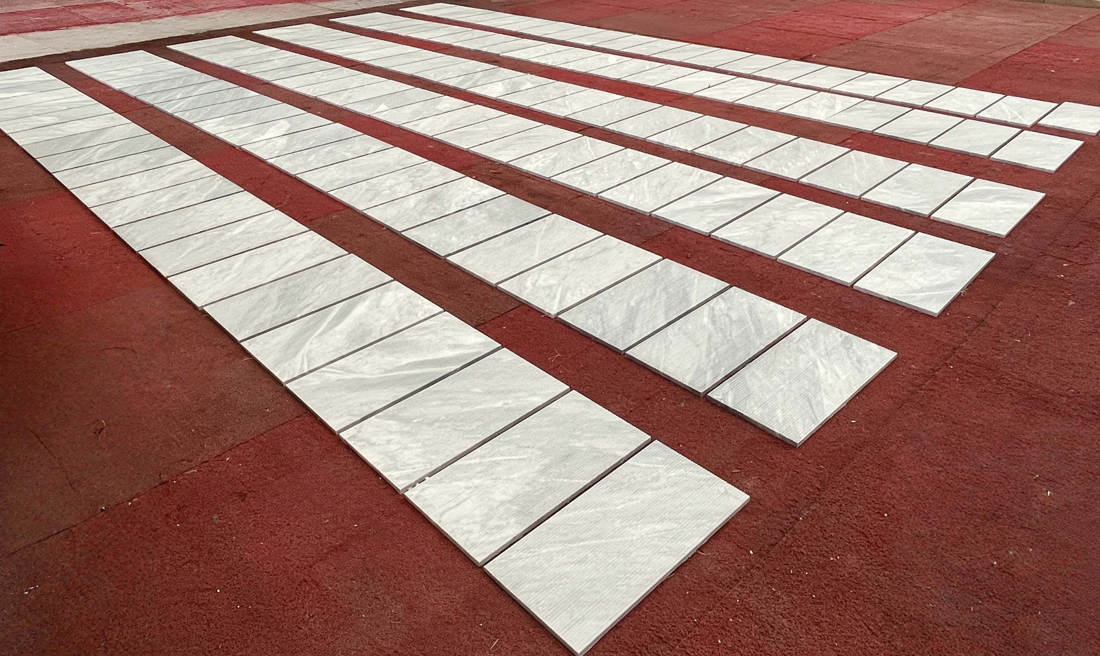 Perspective view of an extensive factory floor layout of fluted marble tiles, emphasizing textured lines and scale.