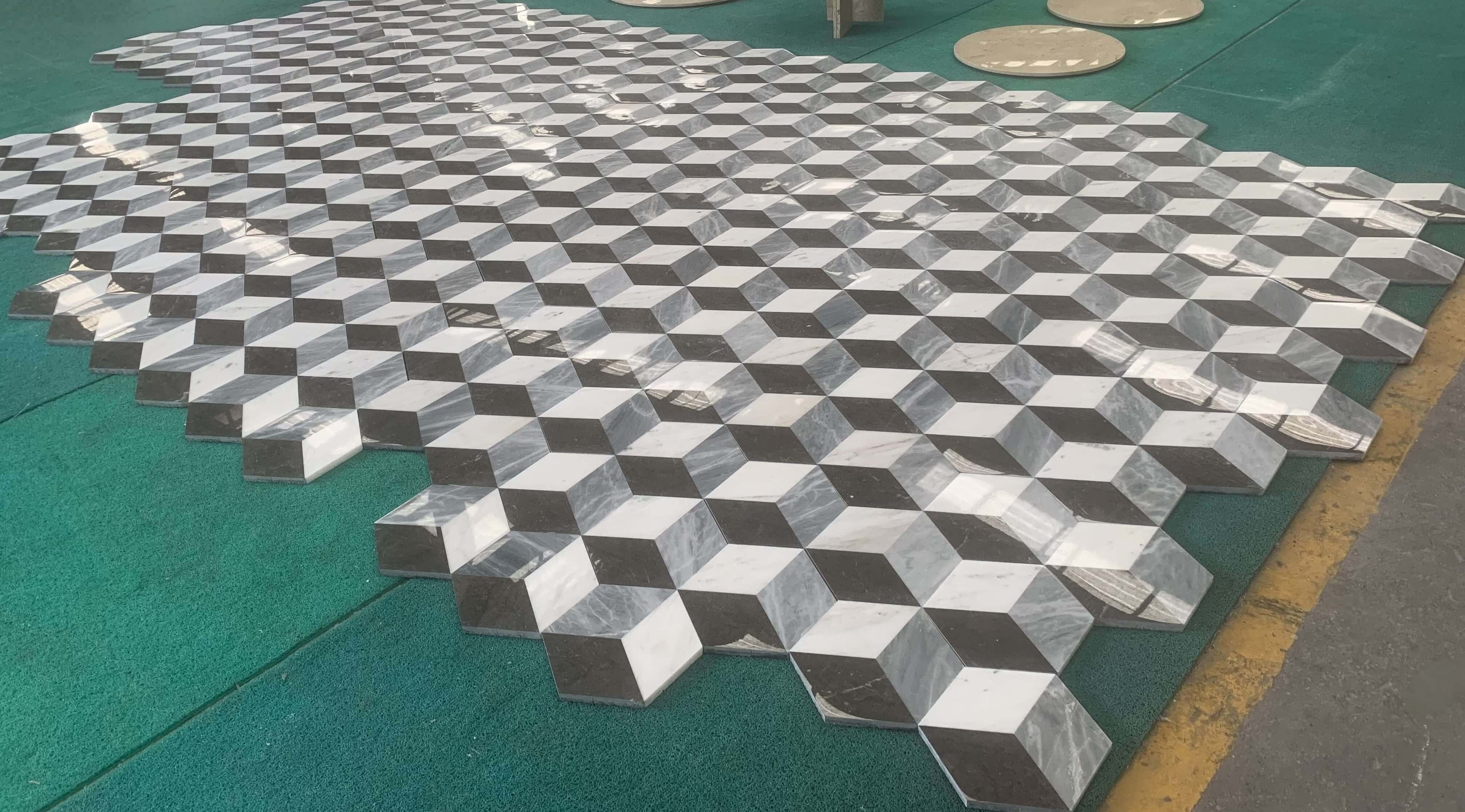 Wide angle dry lay pattern highlighting interlocking seamless fit of white, gray, and black 3D waterjet marble tiles.
