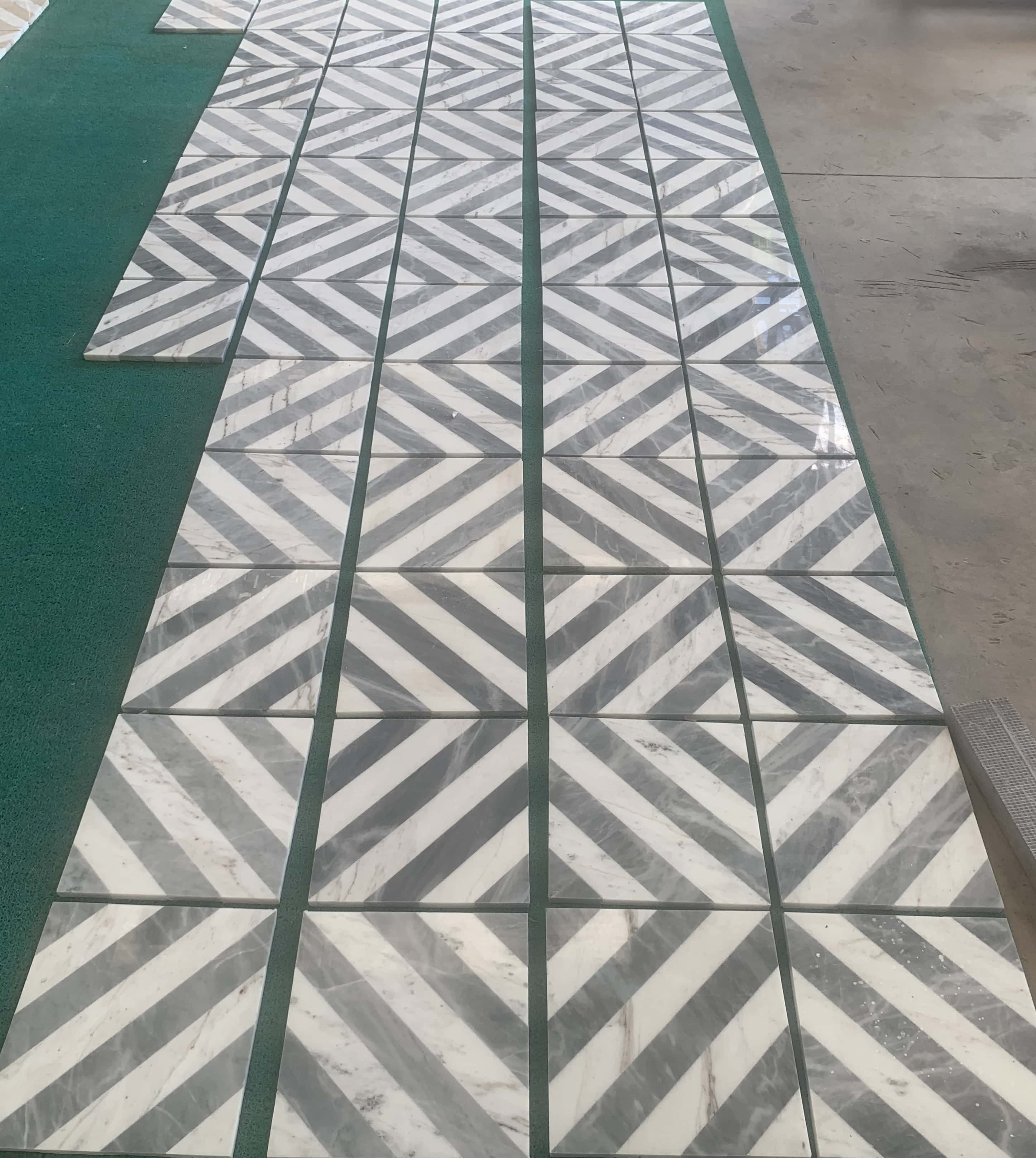 Straight-on view of vertical chevron pattern alignment using 12x12 white and gray waterjet natural marble tiles.