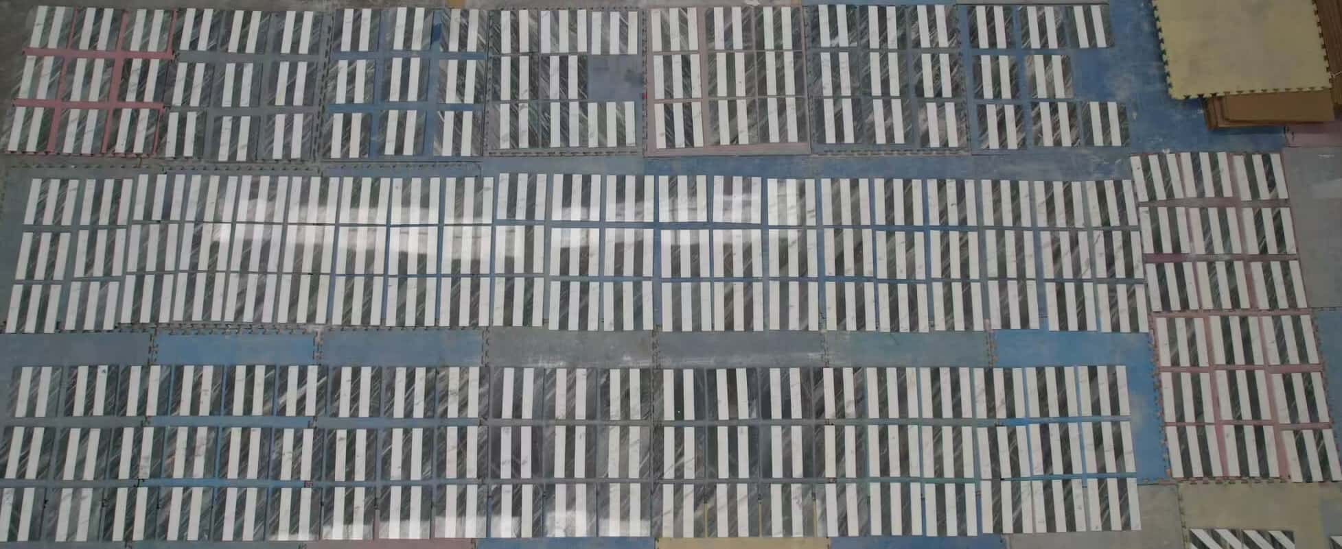 Top view of large quantity factory dry-lay inspection showing sorted Snow Mountain White and Carrara Gray marble tiles.