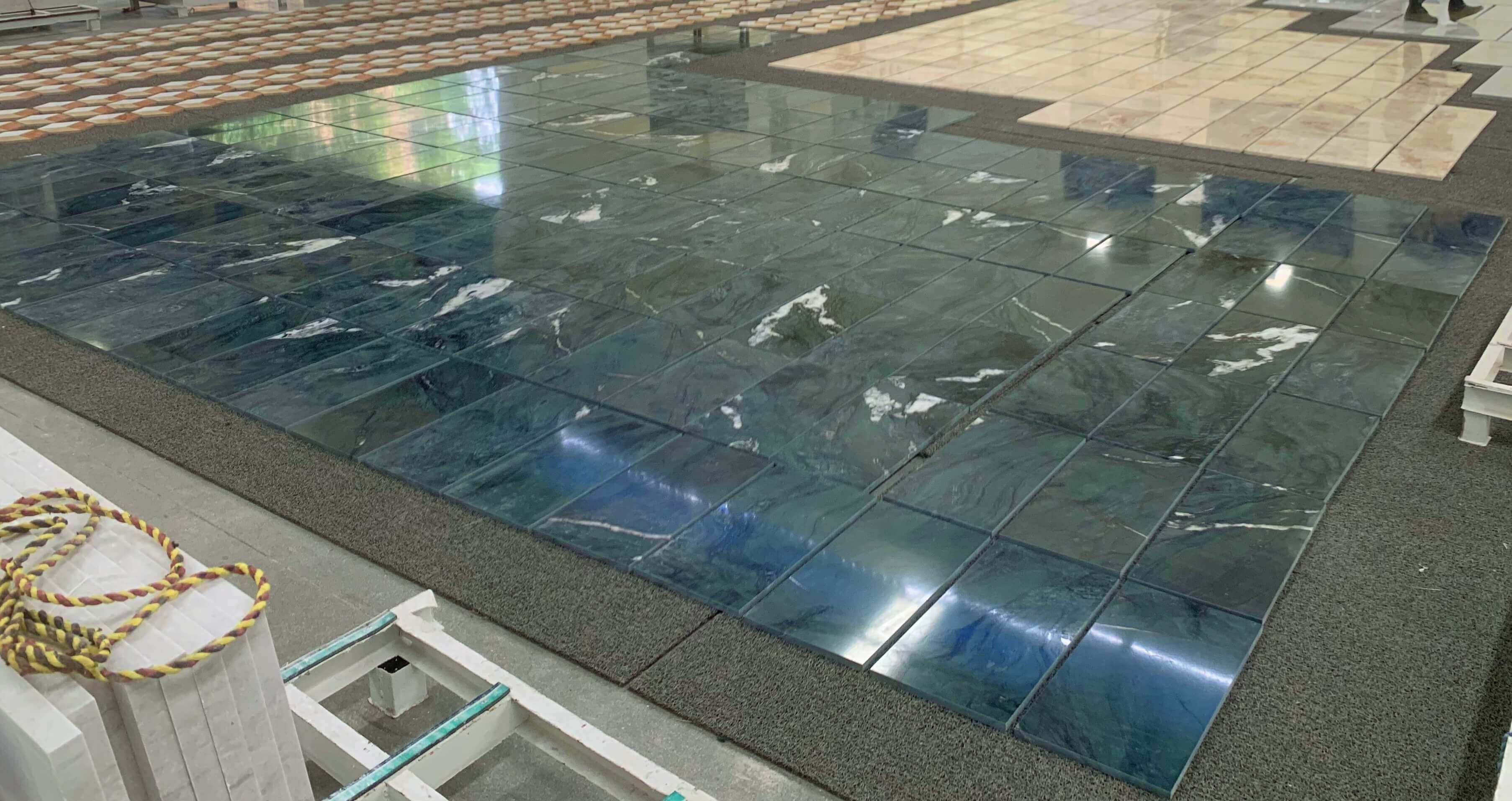 Factory display of polished diamond green stone tile, showcasing continuous emerald veining suitable for wall & floor use.