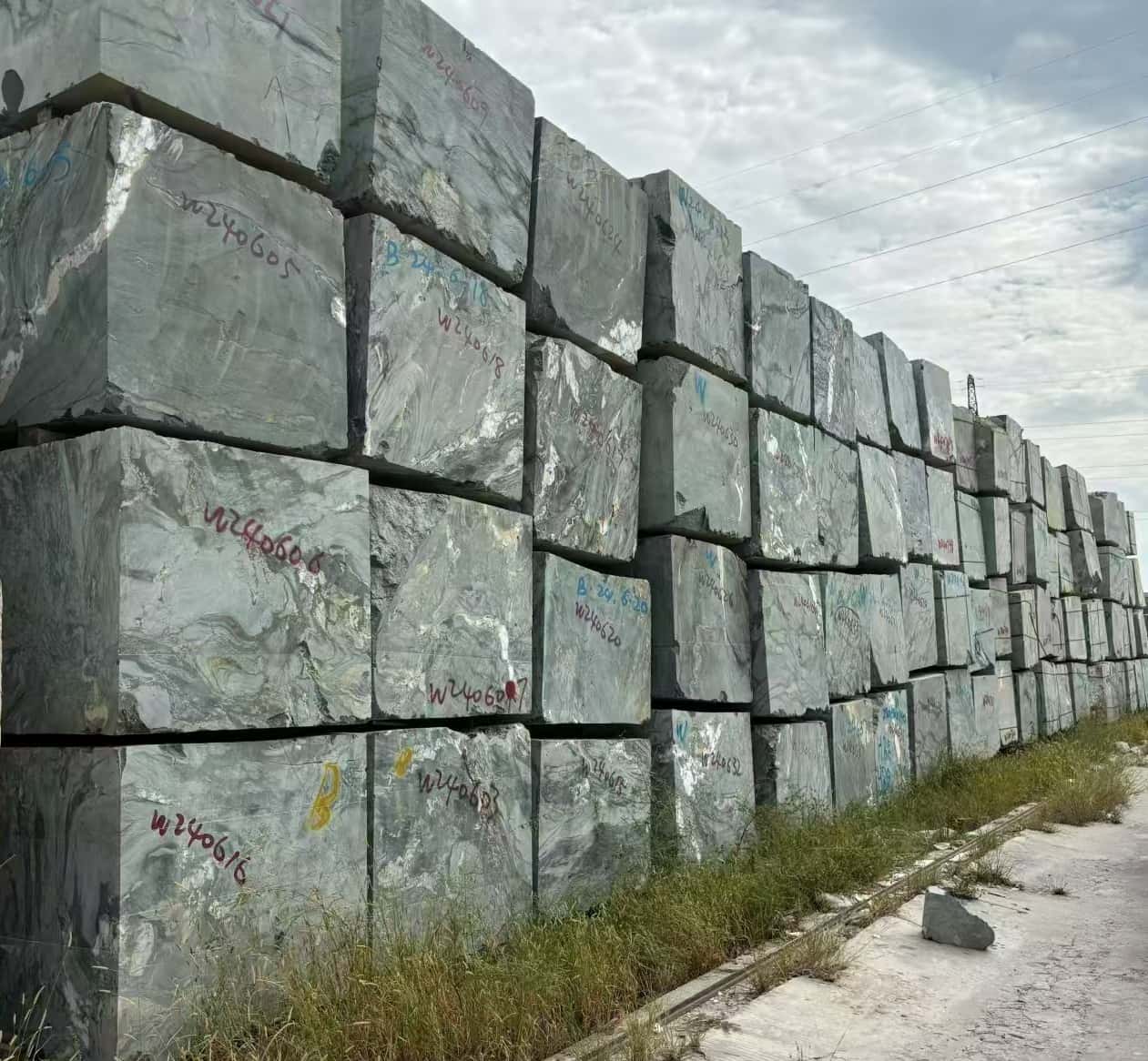 Raw diamond green natural marble blocks stacked at the quarry, showcasing the authentic source of our luxury stone tiles.