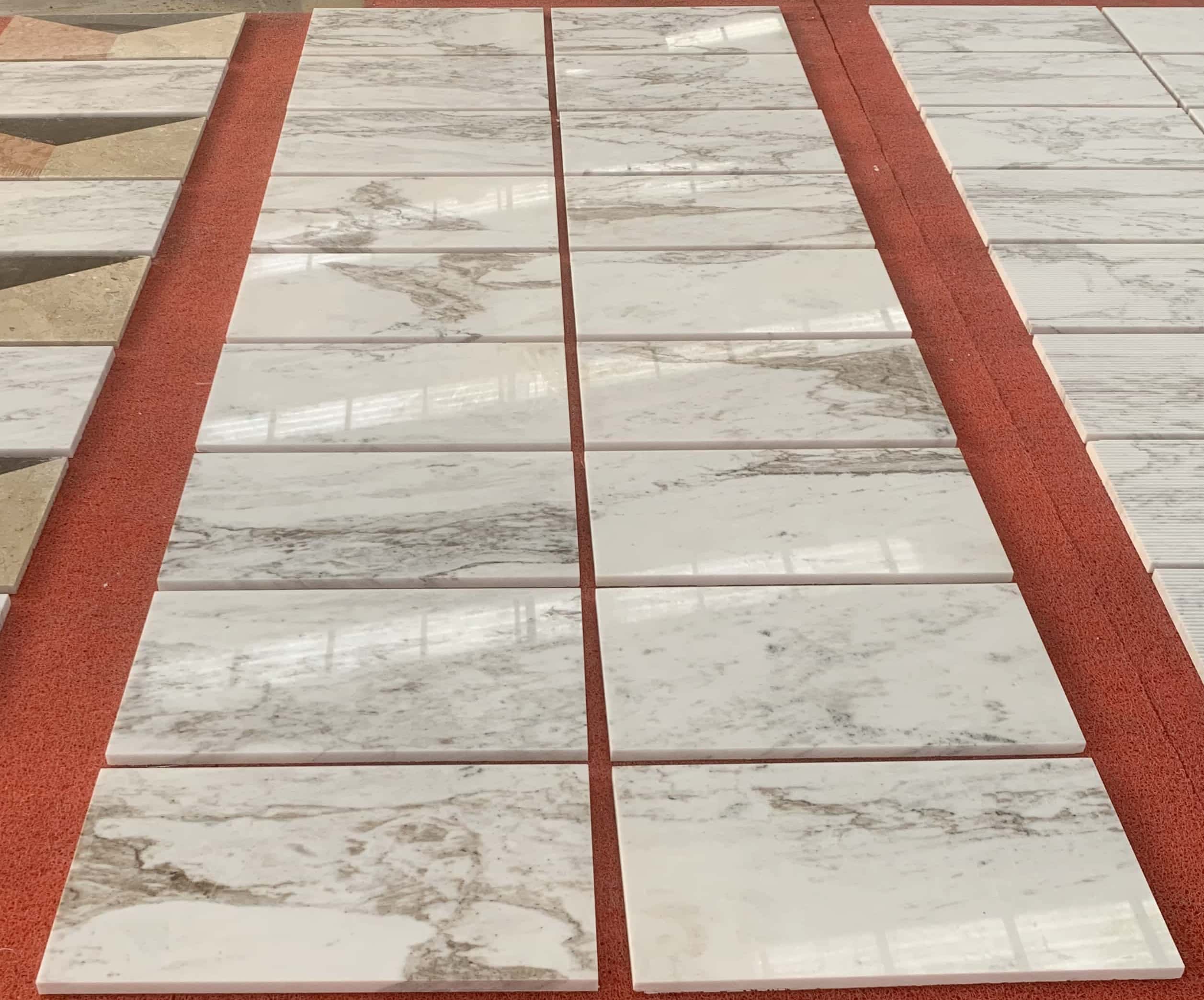 High-end natural stone for walls, showing multiple 12x24 polished white marble tiles arranged during factory inspection.