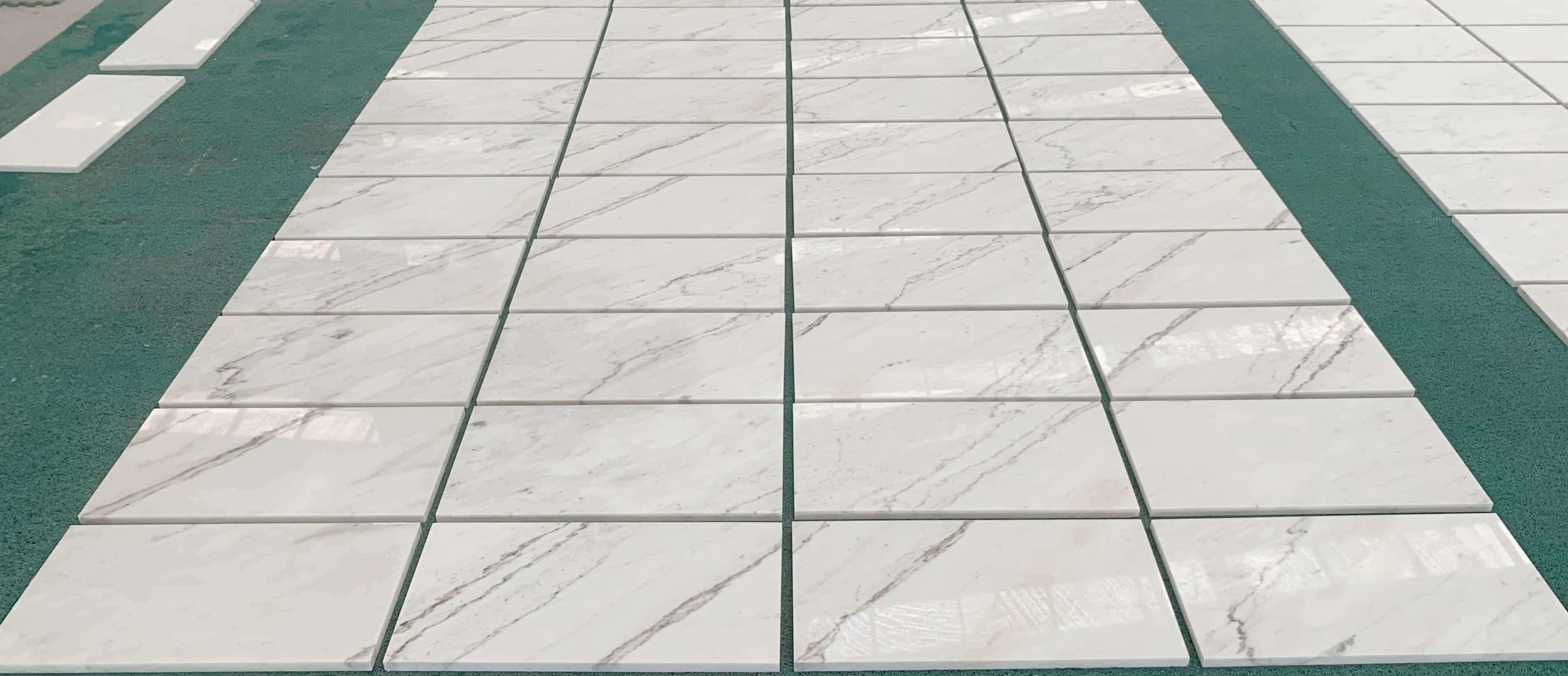 Factory inspection of polished white marble stone tiles, laid out to display natural variation for a living room floor.