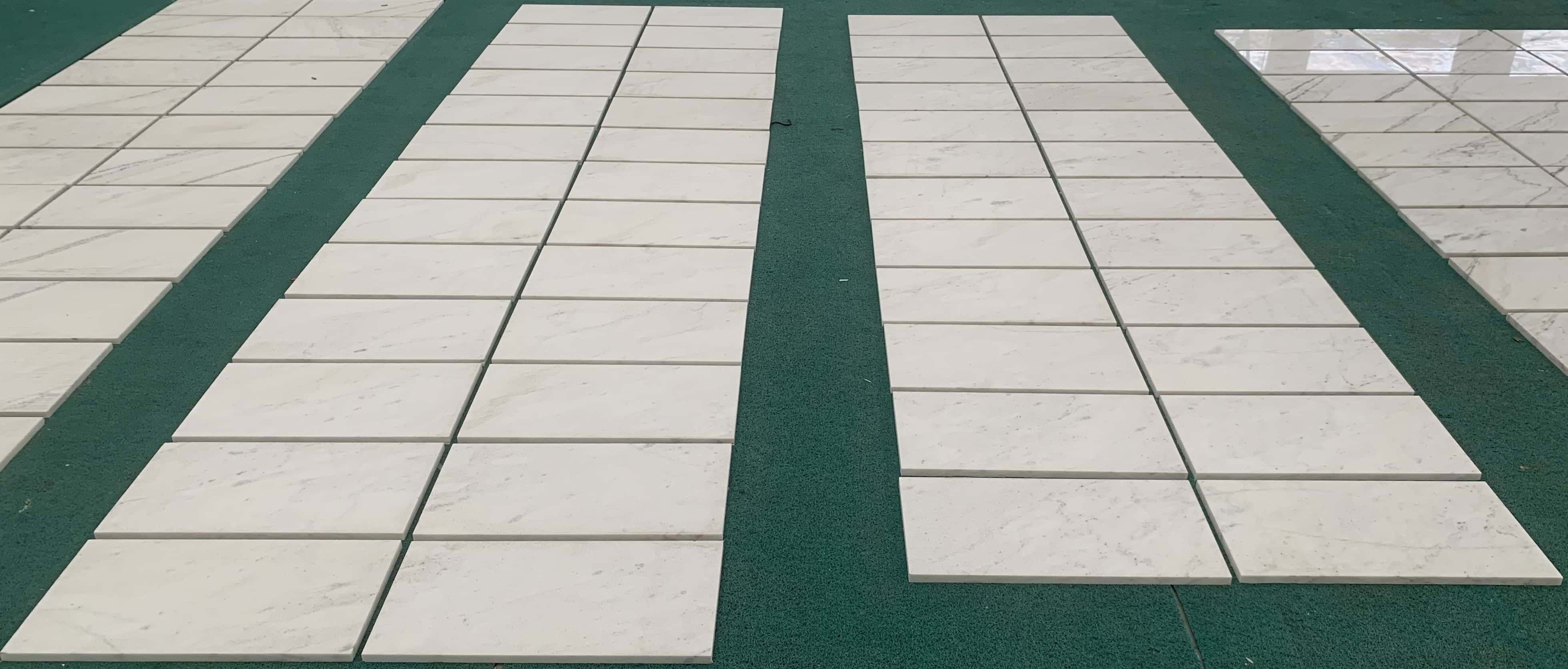 Multiple 12x24 Snow Mountain White FS textured marble wall tiles arranged on factory floor for natural variation dry-lay.