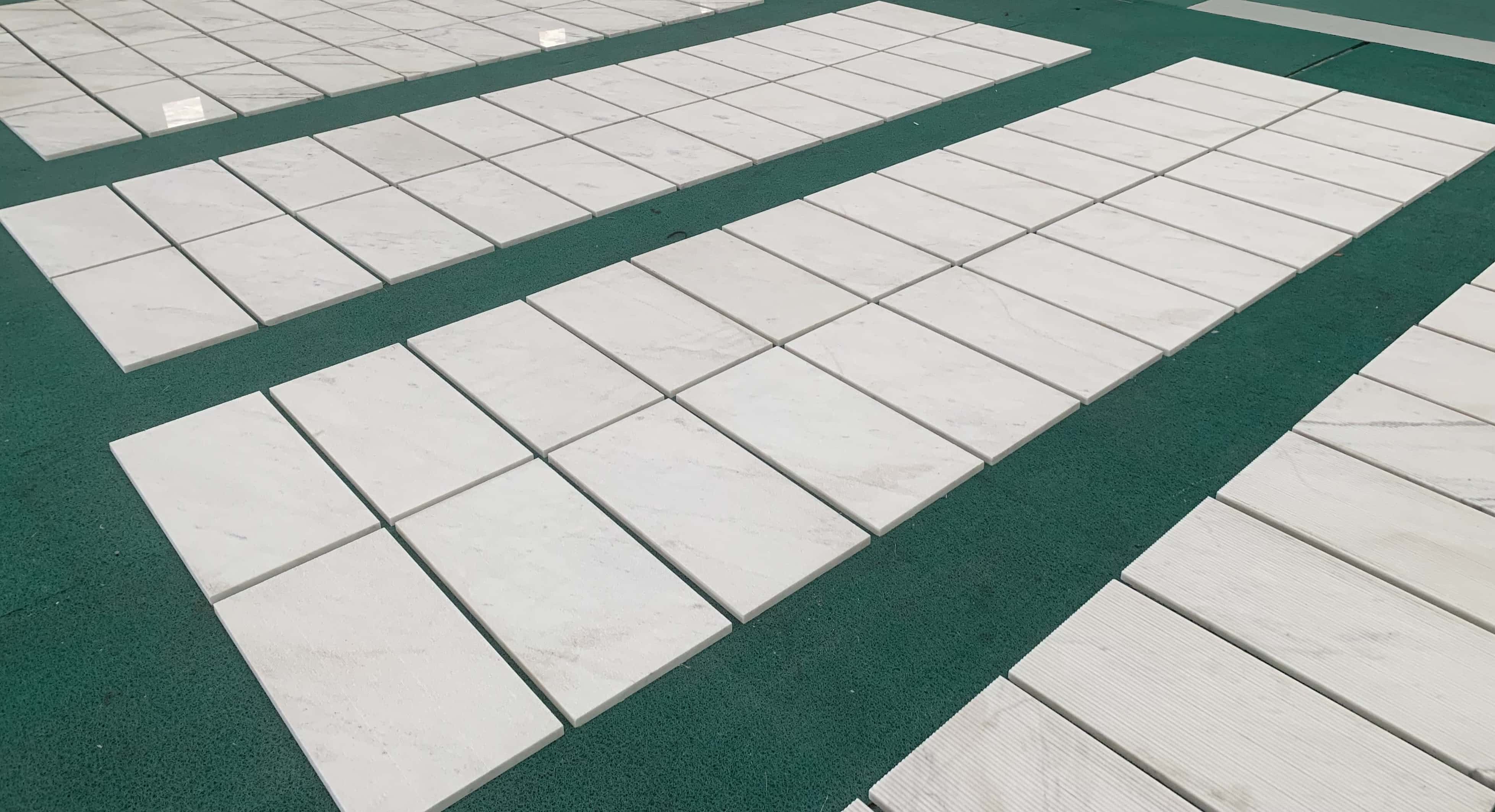Large scale production dry-lay of Snow Mountain White FS textured marble wall tiles with fine linear grooved patterns.