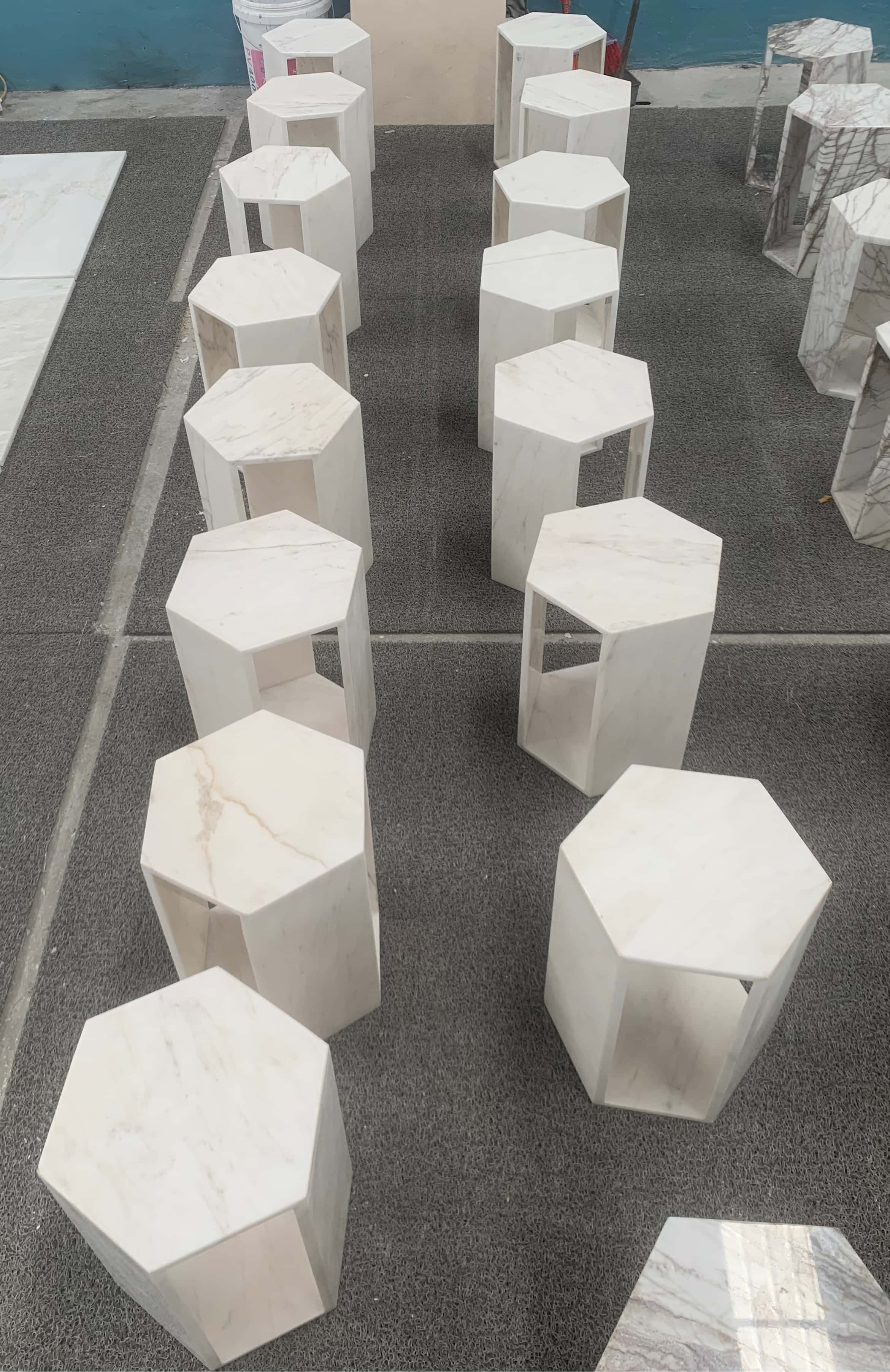 A row of freshly crafted Snow Mountain White marble hexagon side tables in honed finish on the factory floor.