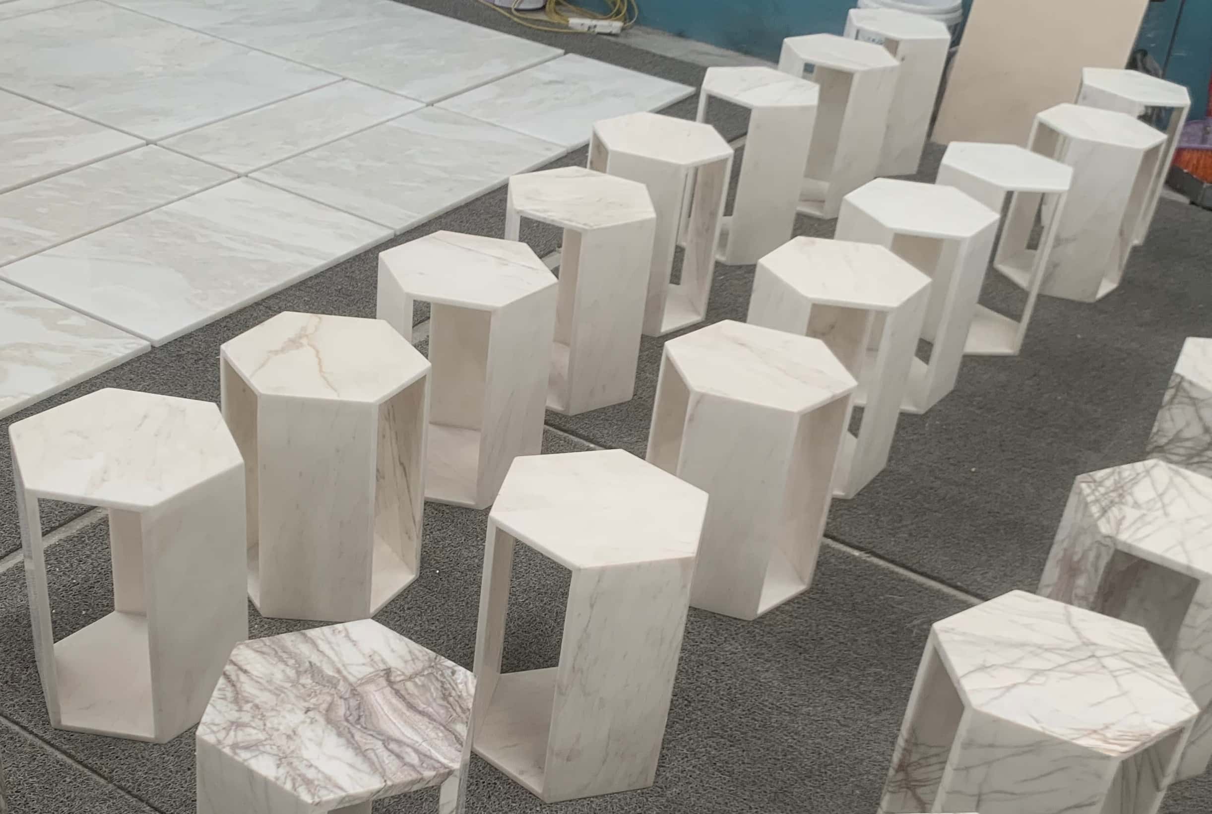 Quality inspection of assembled hollow Snow Mountain White marble hexagon side tables in the manufacturing workshop.