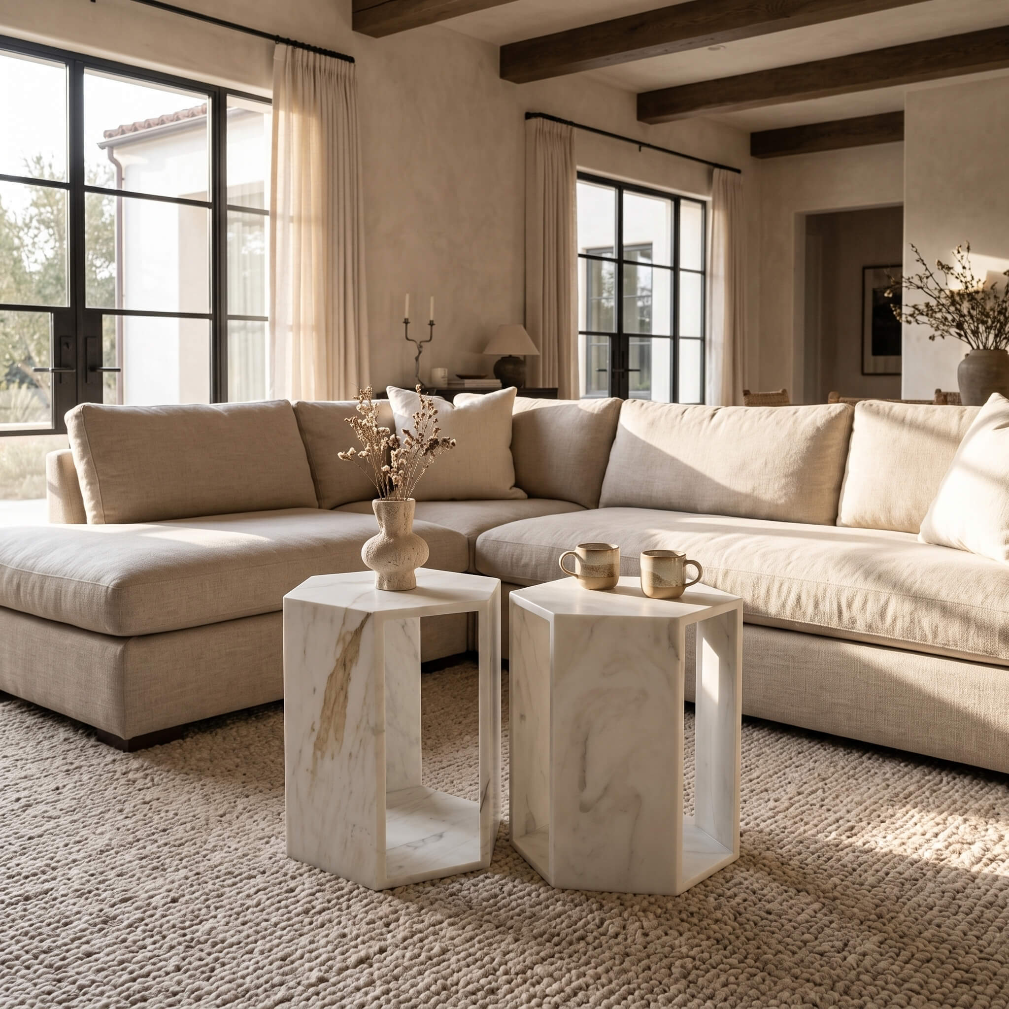 A paired set of honed Snow Mountain White marble hexagon side tables arranged together in front of a warm beige sectional.