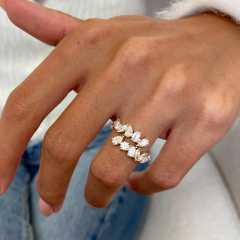 Top-down perspective of an open shank diamond ring on a hand, showing how the emerald and pear cut stones wrap around the finger for a floating effect.
