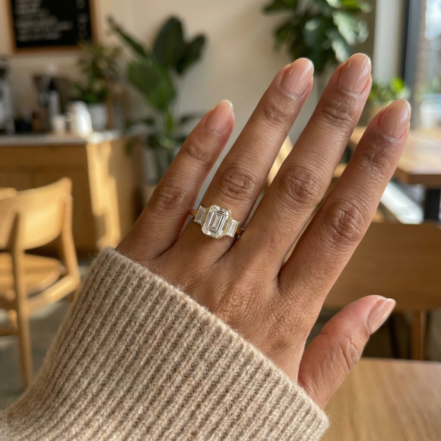 A 1.5ct emerald cut lab created diamond ring shown on a woman's size 6 hand, demonstrating the face-up size and finger coverage of the emerald cut stone with baguette accents.