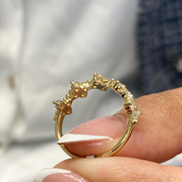 Side profile view of a floral diamond ring held in fingers, highlighting the 14k gold setting craftsmanship and band thickness.