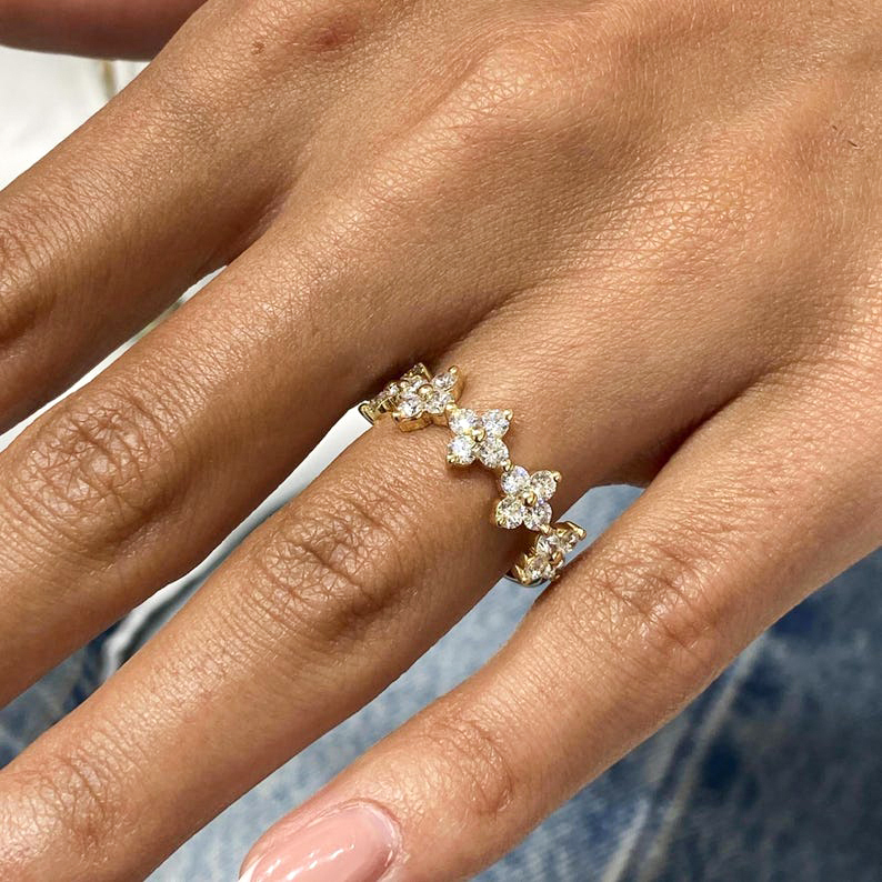 Woman's hand wearing a 14k gold floral cluster wedding band, showcasing the sparkling lab-grown diamonds in a nature-inspired design.