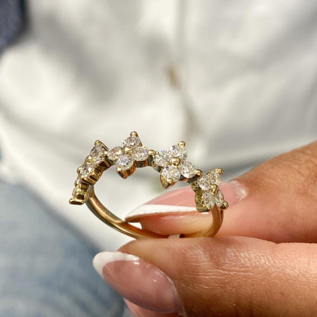 Close-up of a unique flower diamond ring featuring five floral clusters of round lab-grown diamonds, held to show brilliance.