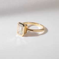 Sleek 14K gold band and full bezel setting securing an emerald cut lab created diamond.