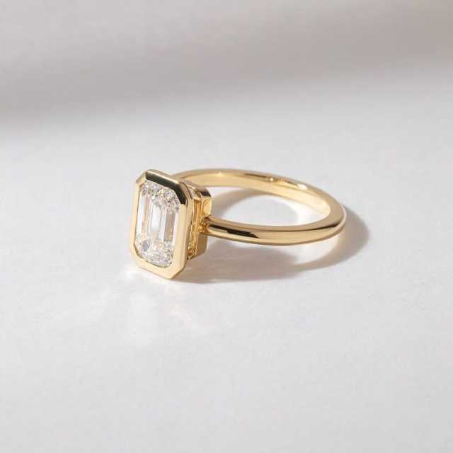 Sleek 14K gold band and full bezel setting securing an emerald cut lab created diamond.