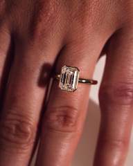 Woman wearing a 2 carat emerald cut bezel set lab grown diamond engagement ring on her hand