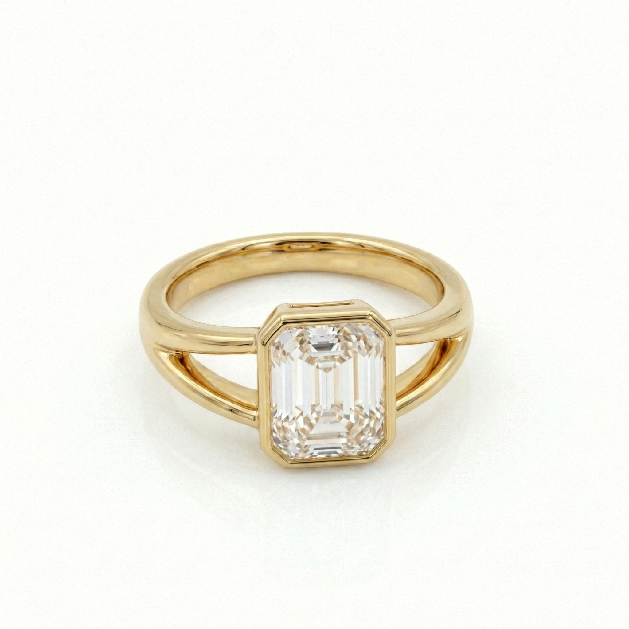 Flat lay view of a bespoke 14K solid gold bezel engagement ring featuring a 2ct emerald cut lab diamond.