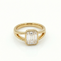 Flat lay view of a bespoke 14K solid gold bezel engagement ring featuring a 2ct emerald cut lab diamond.