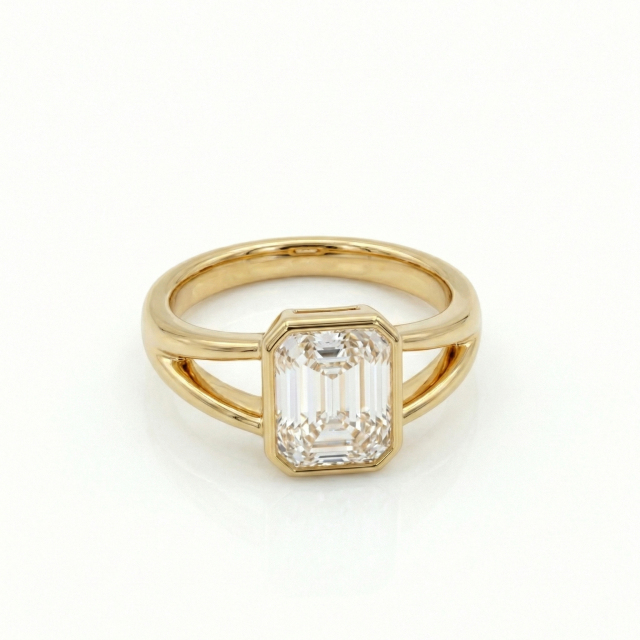 Flat lay view of a bespoke 14K solid gold bezel engagement ring featuring a 2ct emerald cut lab diamond.