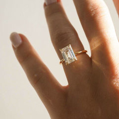 Extreme close-up of a 4-carat emerald cut lab diamond on a finger reflecting bright light, showcasing the exact optical brilliance of an earth-mined diamond.