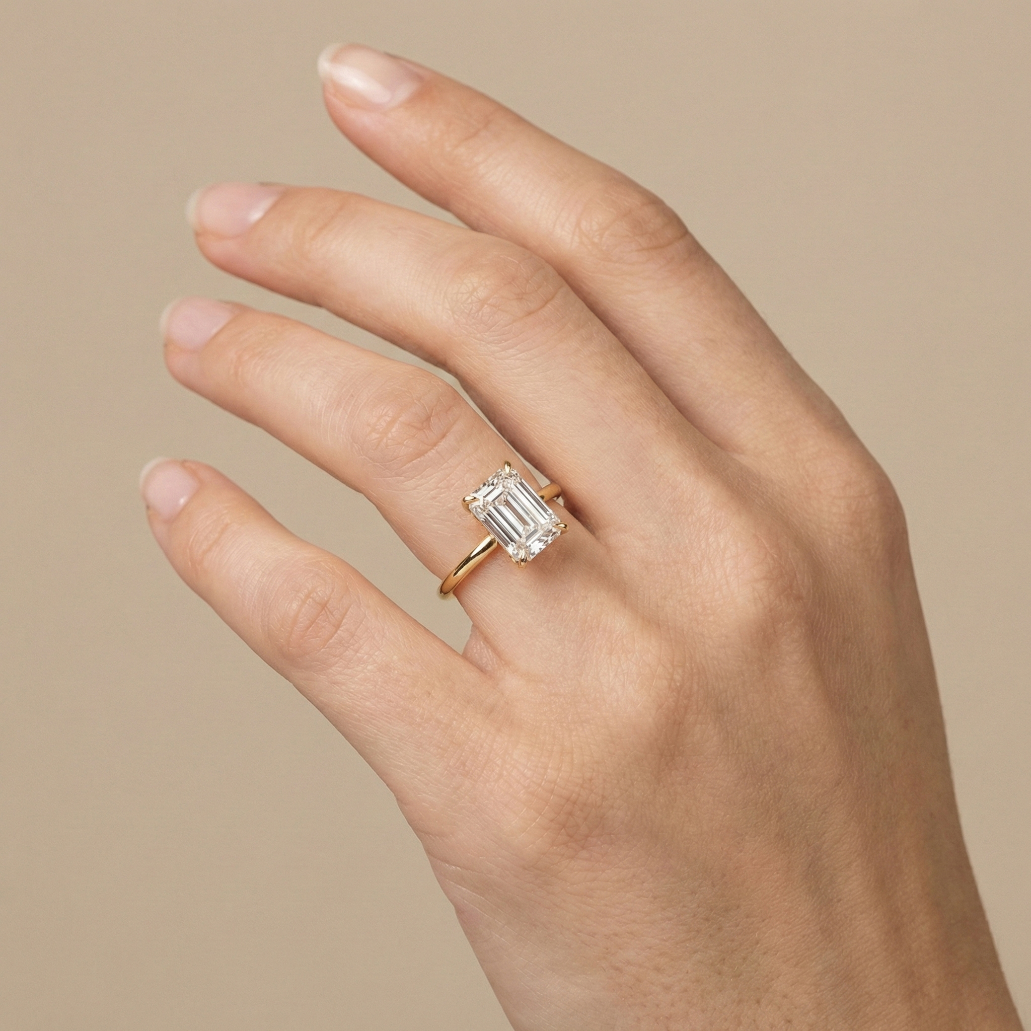 Hand modeling a large 4-carat step-cut emerald lab-grown diamond engagement ring, highlighting the pristine VS1 clarity and perfect proportions.