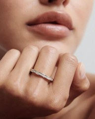 High-fashion close-up of a model resting her face on her hand, elegantly displaying the flawless sparkle of the 18K gold lab-grown diamond eternity ring.