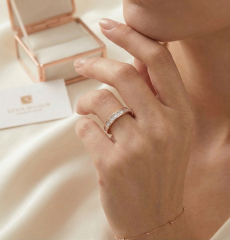 Sophisticated lifestyle shot of a woman wearing the 18K gold princess diamond band, with a luxury jewelry presentation box in the soft-focus background.