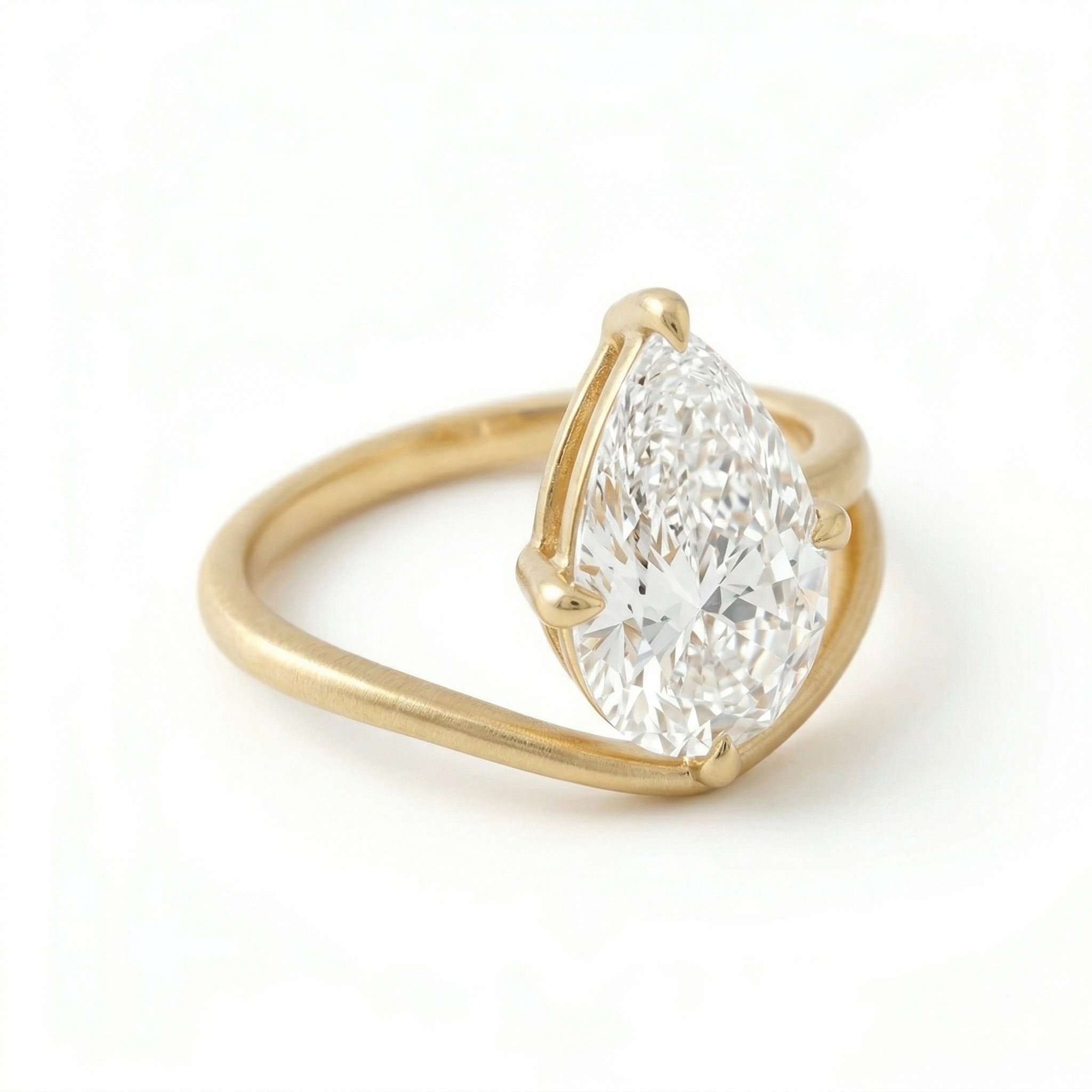 Angled top-down view of a stunning 3 carat pear cut lab grown diamond ring, highlighting the exceptional E color and asymmetrical 14K matte gold bypass design.