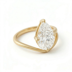 Angled top-down view of a stunning 3 carat pear cut lab grown diamond ring, highlighting the exceptional E color and asymmetrical 14K matte gold bypass design.