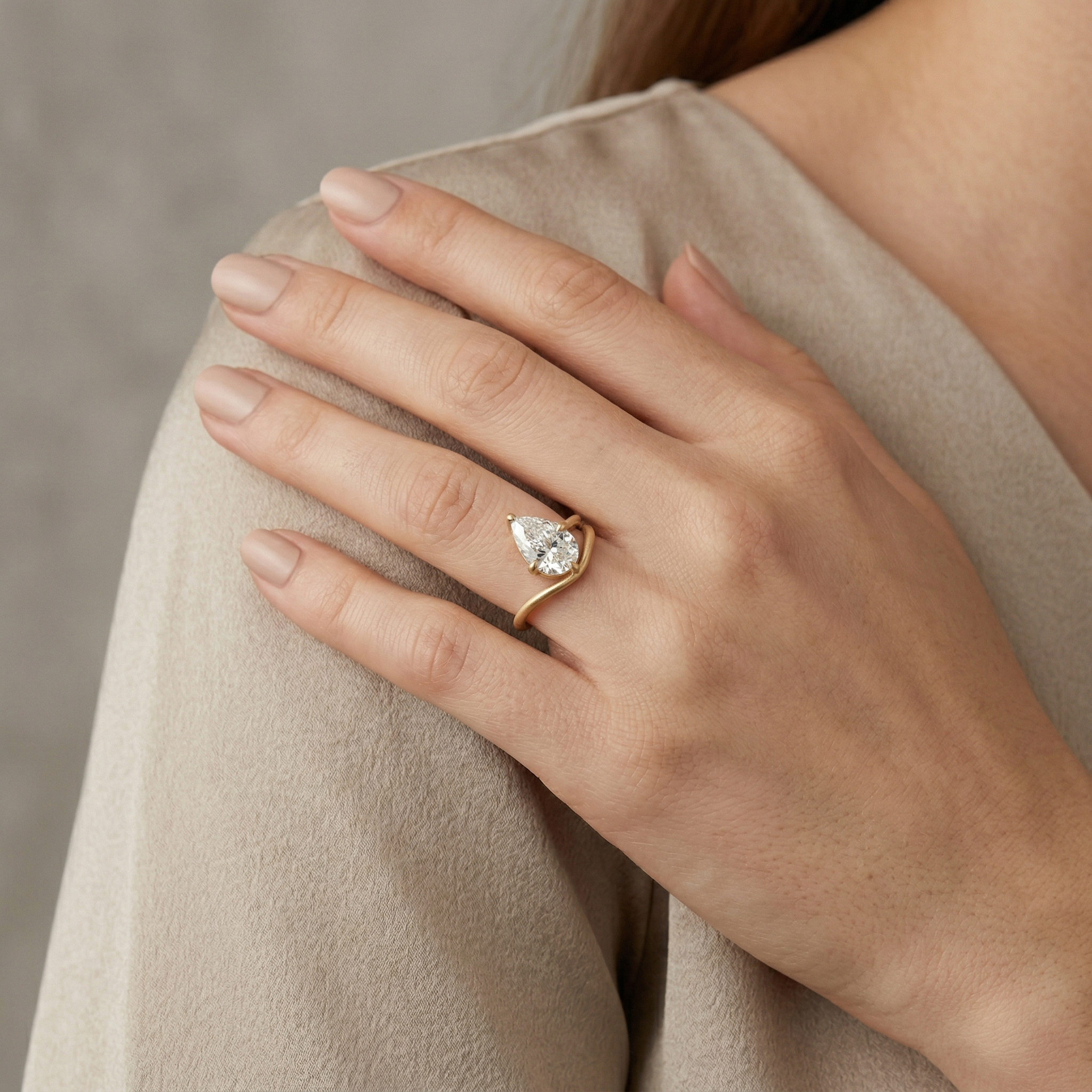 Elegant woman wearing a custom 3ct pear lab diamond engagement ring on her ring finger, showcasing the elongating effect of the teardrop shape and 14K gold band.