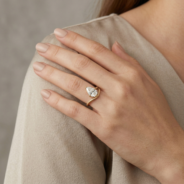 Elegant woman wearing a custom 3ct pear lab diamond engagement ring on her ring finger, showcasing the elongating effect of the teardrop shape and 14K gold band.