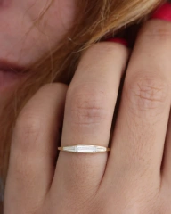 Close up of a woman hand with red nail polish wearing a 14K gold bezel set tapered baguette lab diamond ring.