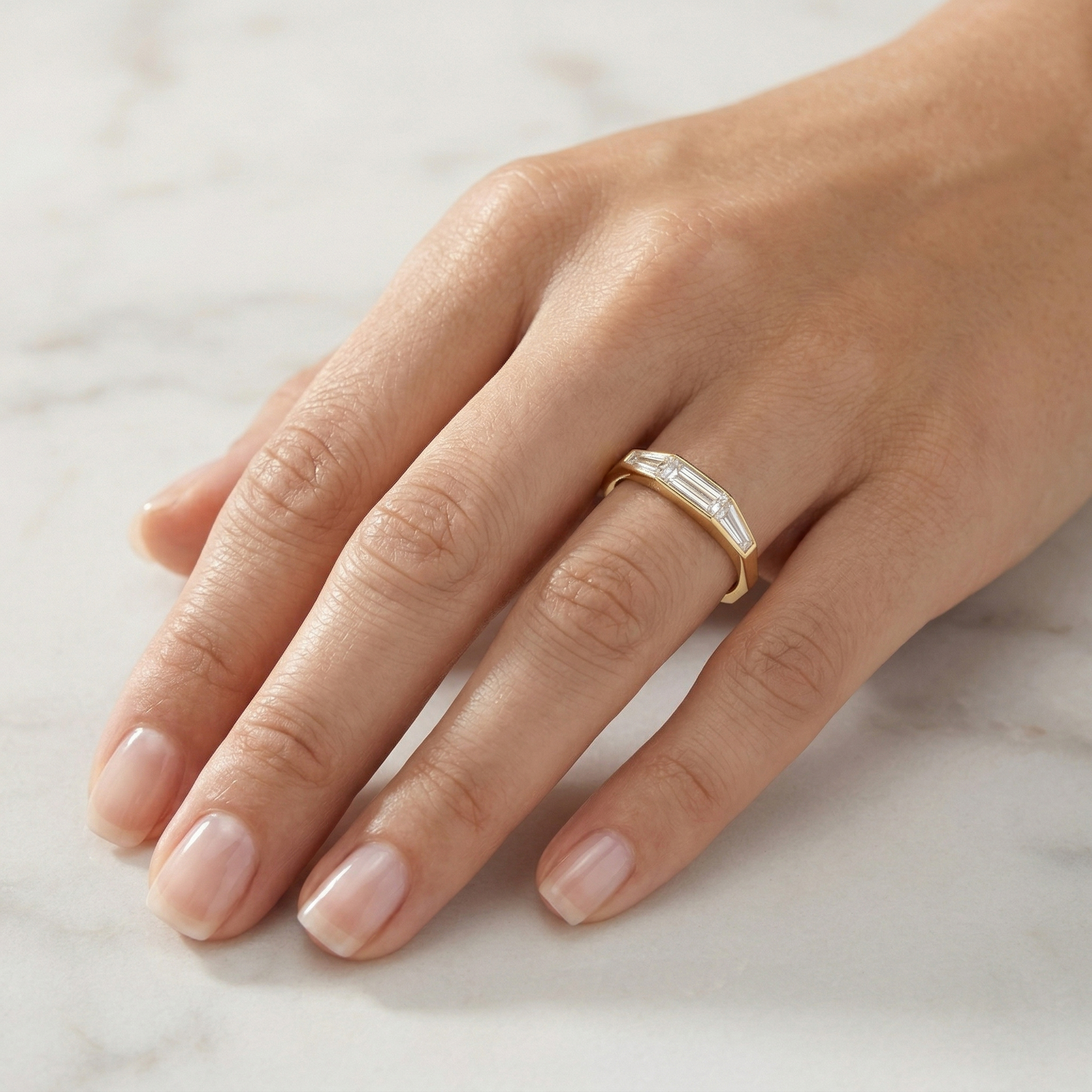 Model hand wearing a minimalist Art Deco inspired 14K gold tapered baguette lab diamond ring.