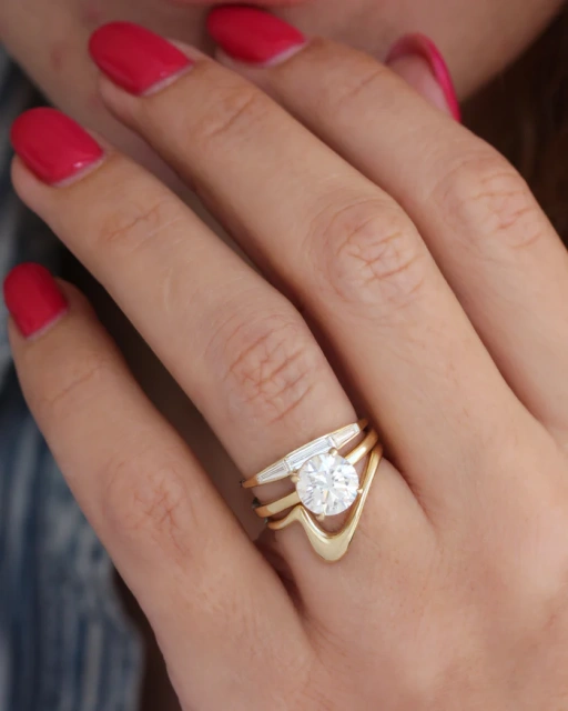 14K gold bezel set baguette lab diamond wedding band stacked flush with a round brilliant solitaire engagement ring and a curved gold band.