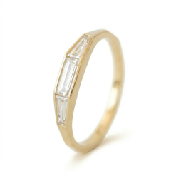 Angle view of a 14K yellow gold stackable wedding band featuring bezel set tapered and straight baguette lab grown diamonds.